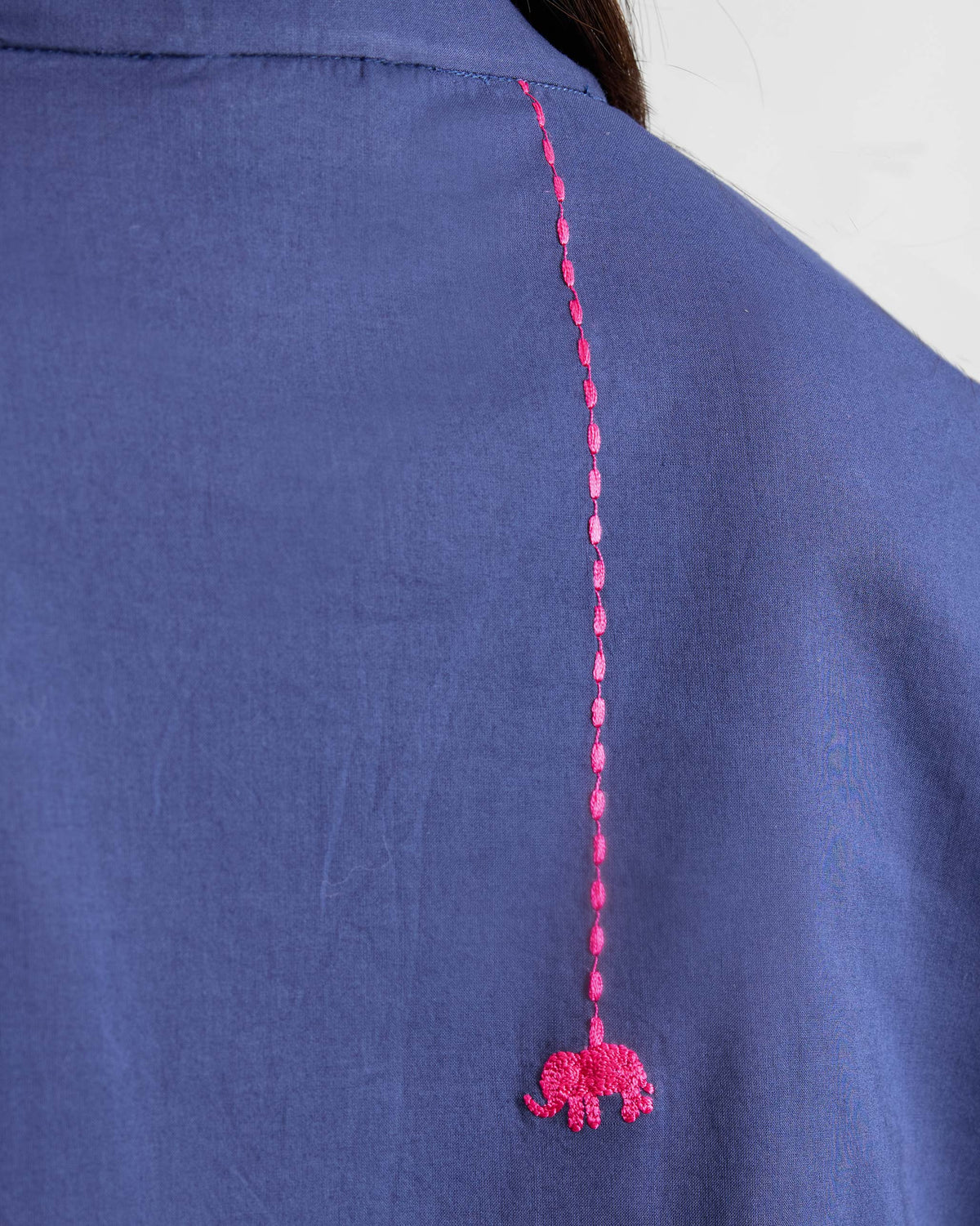 Close-up of pink elephant embroidery on the back of an ink blue kurta.