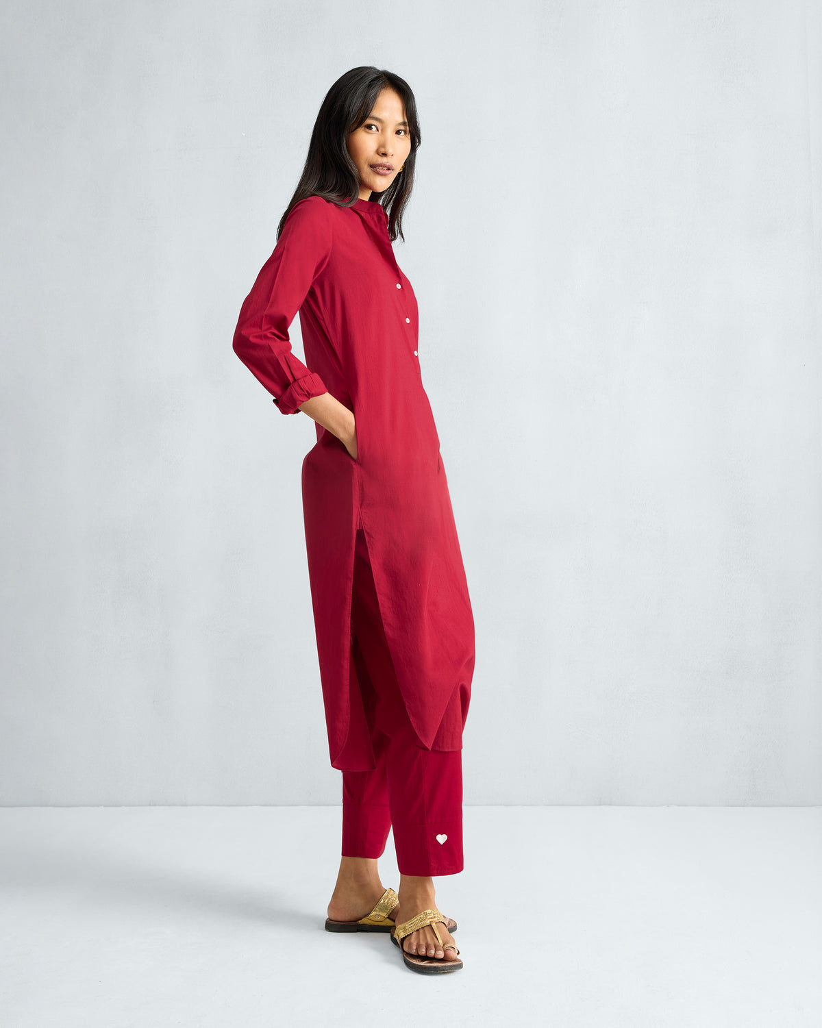 Side view of a red long kurta set with a white heart on the pant hem.