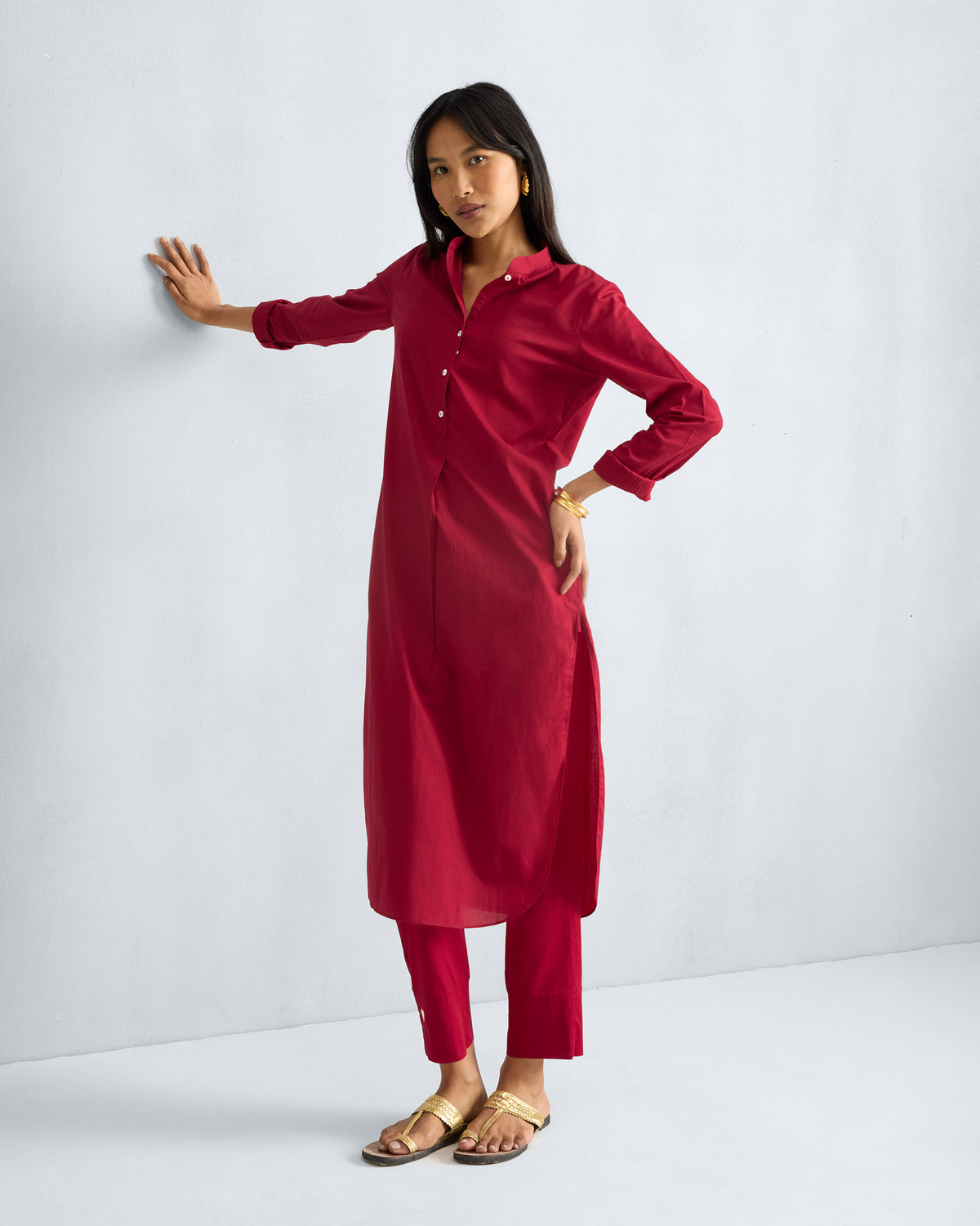 Person wearing a red long kurta with rolled sleeves and a white button placket.