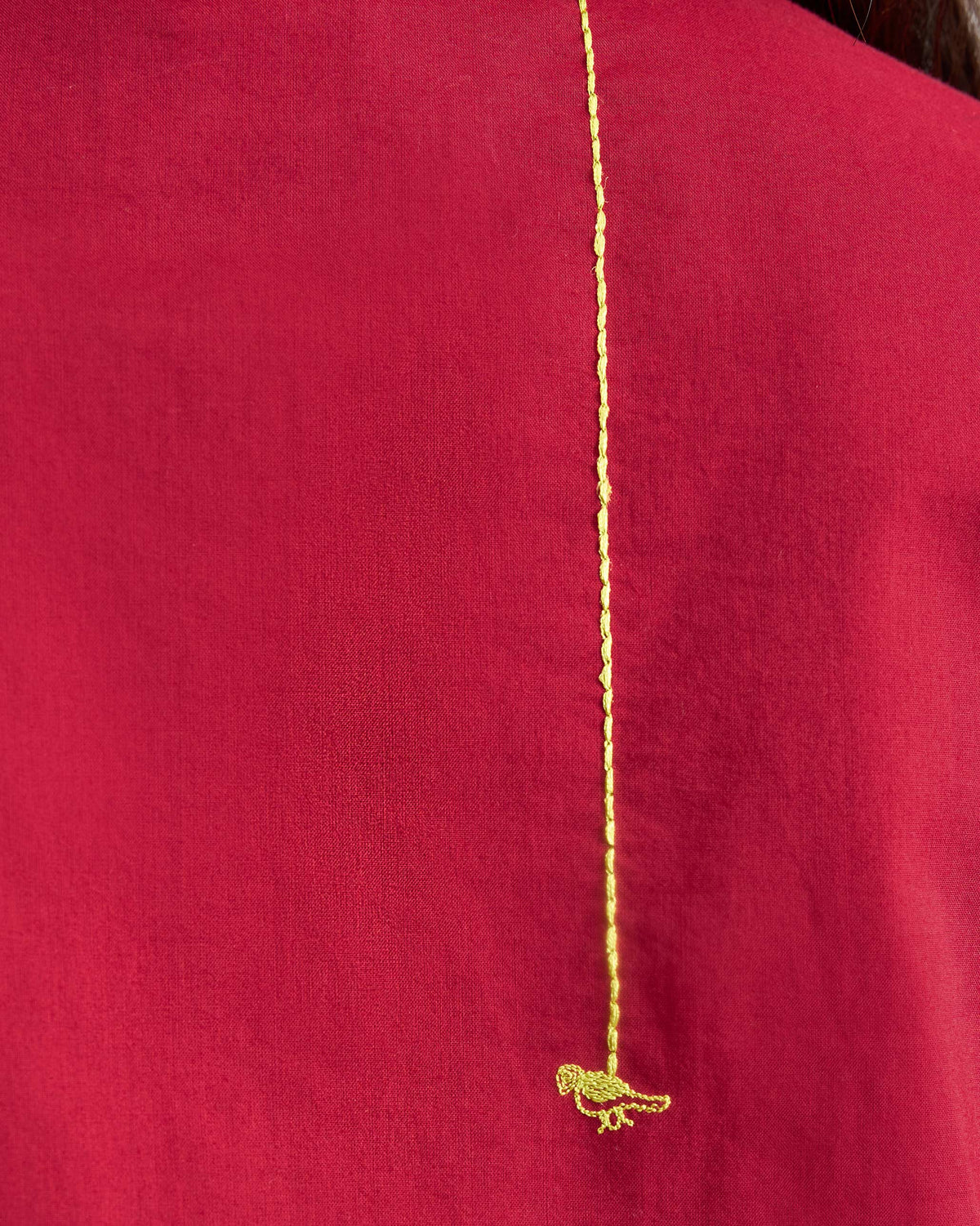 Close-up of gold bird embroidery on the back of a red kurta.