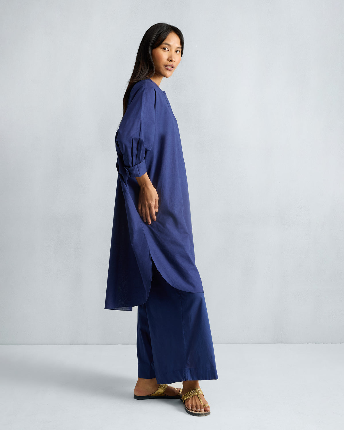 Side view of the Lazy Sunday tunic in ink blue with a curved hem and gathered sleeve cuffs.