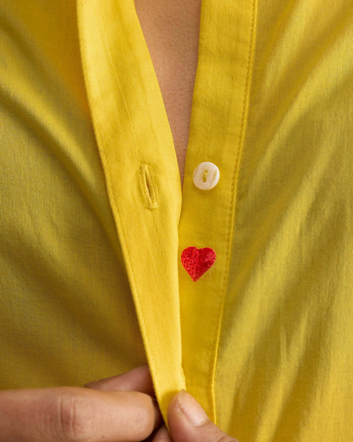 Close-up of a red heart embroidered inside the yellow kurta placket.