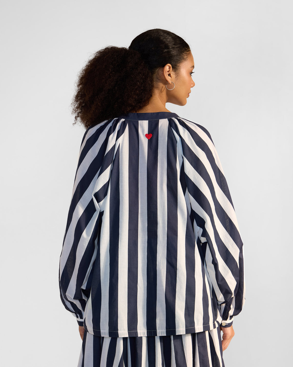 Back of a navy and white striped Zaya top with a red heart embroidery.