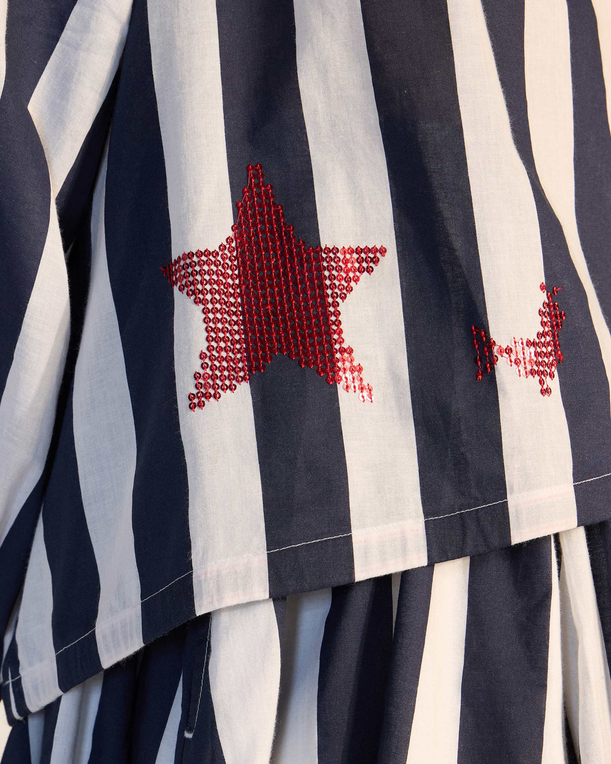 Close-up of a red sequin star on a navy and white striped Zaya top.