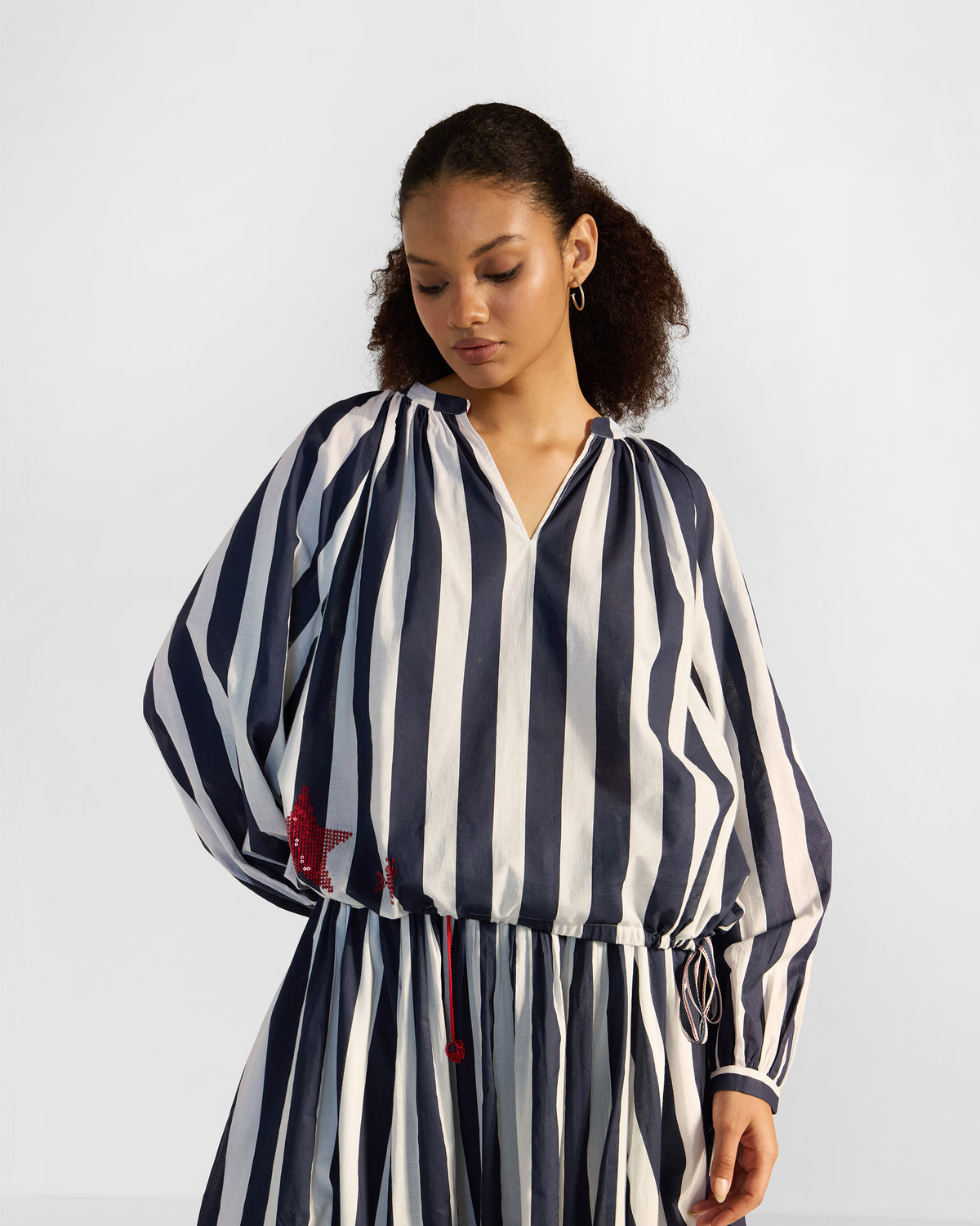 Person wearing a navy and white striped Zaya top with a red star and drawstring hem.