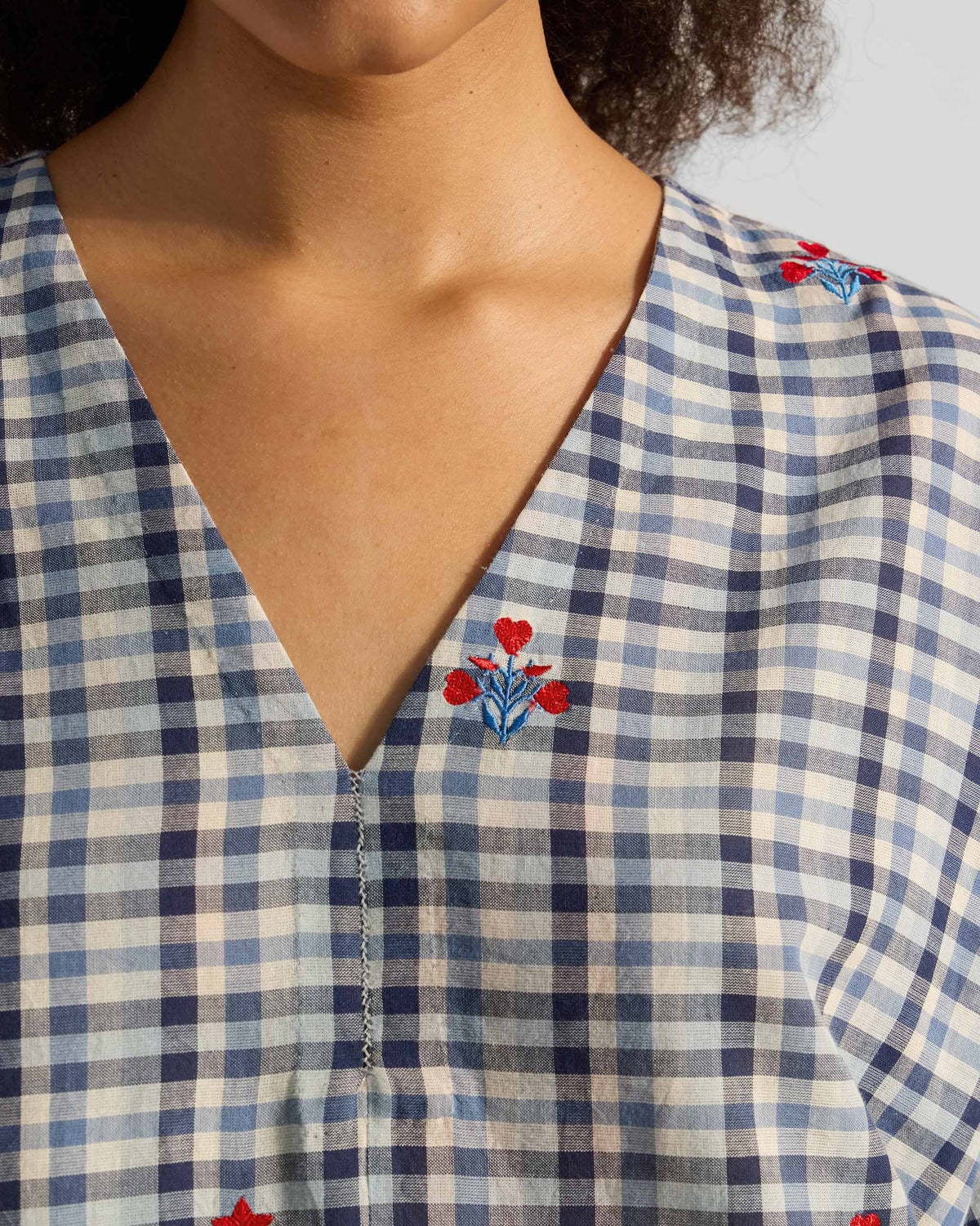 Close-up of the Aava kurta V-neck with red heart embroidery on blue and white checks.
