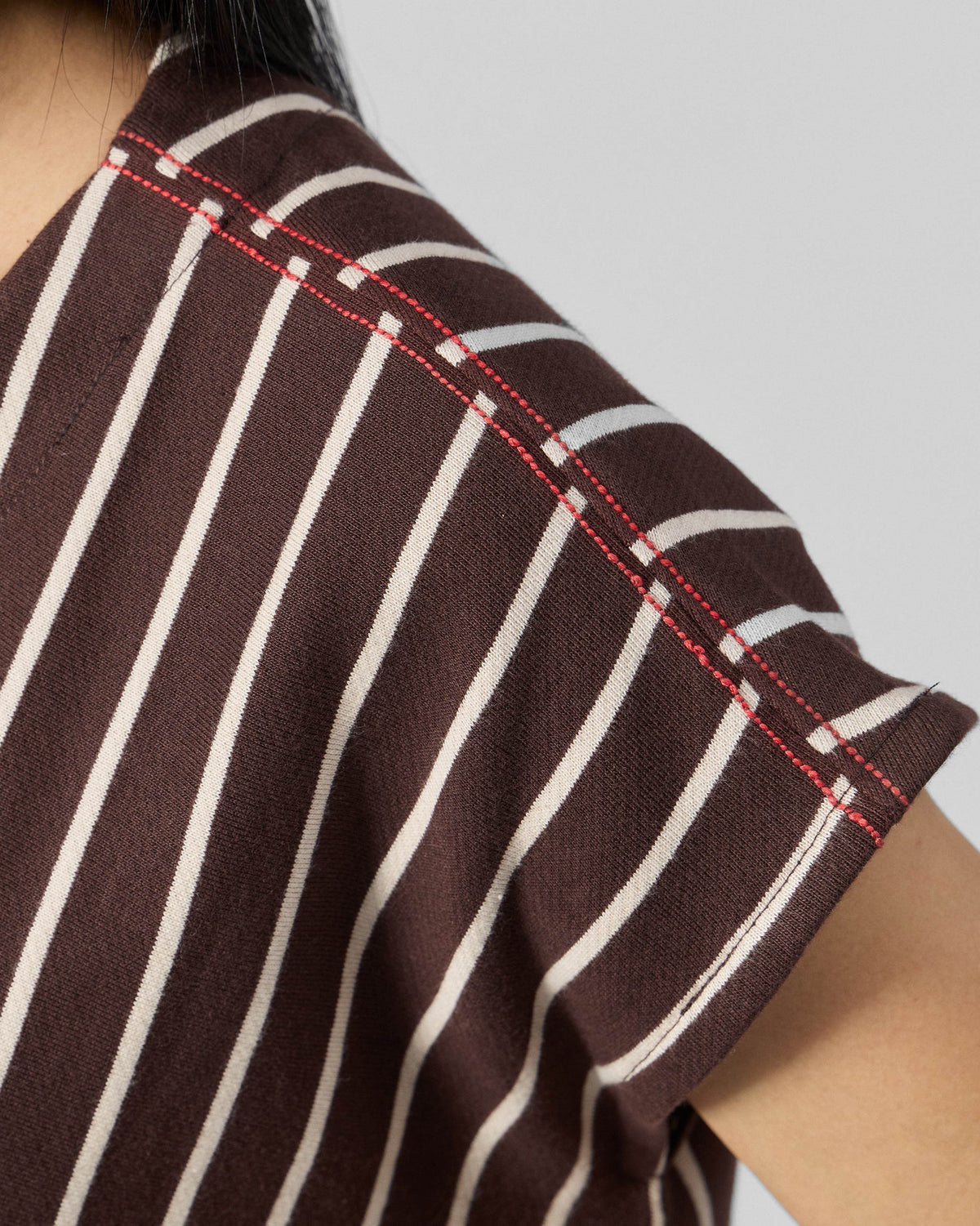 Close-up of red contrast stitching on the shoulder of a striped kaftan top.