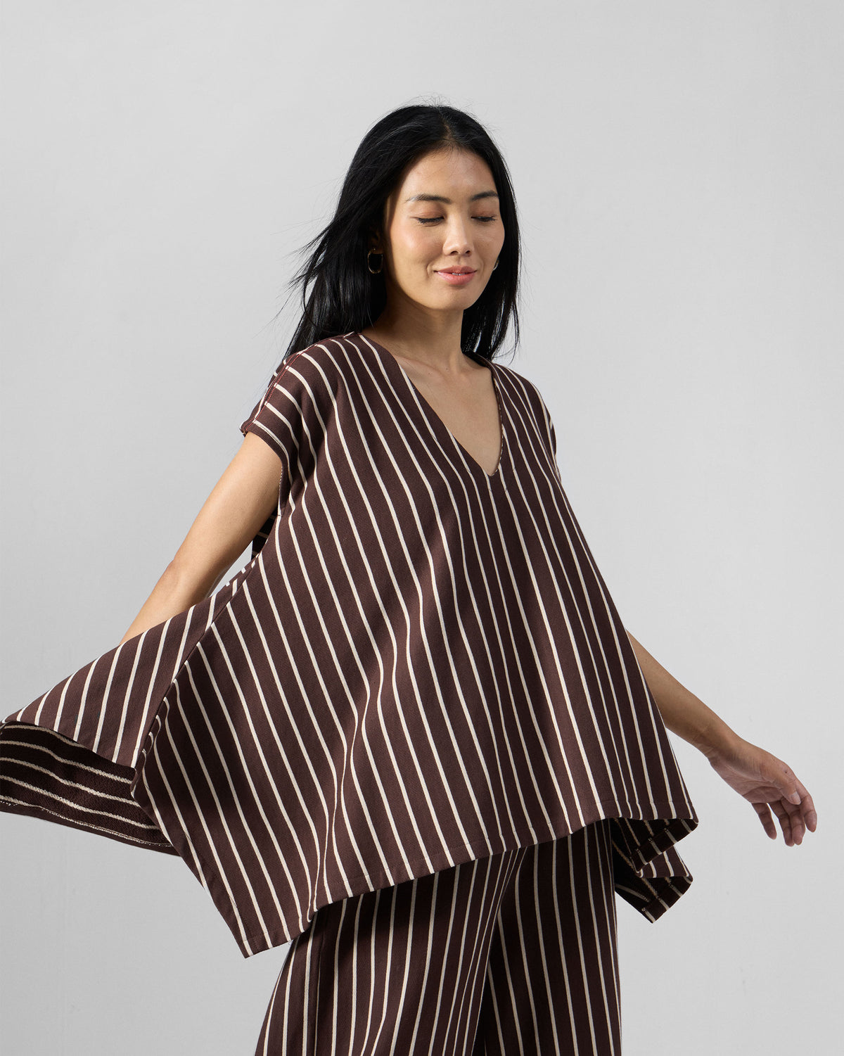 Person wearing a brown and ivory striped kaftan top set showing a flared hem.