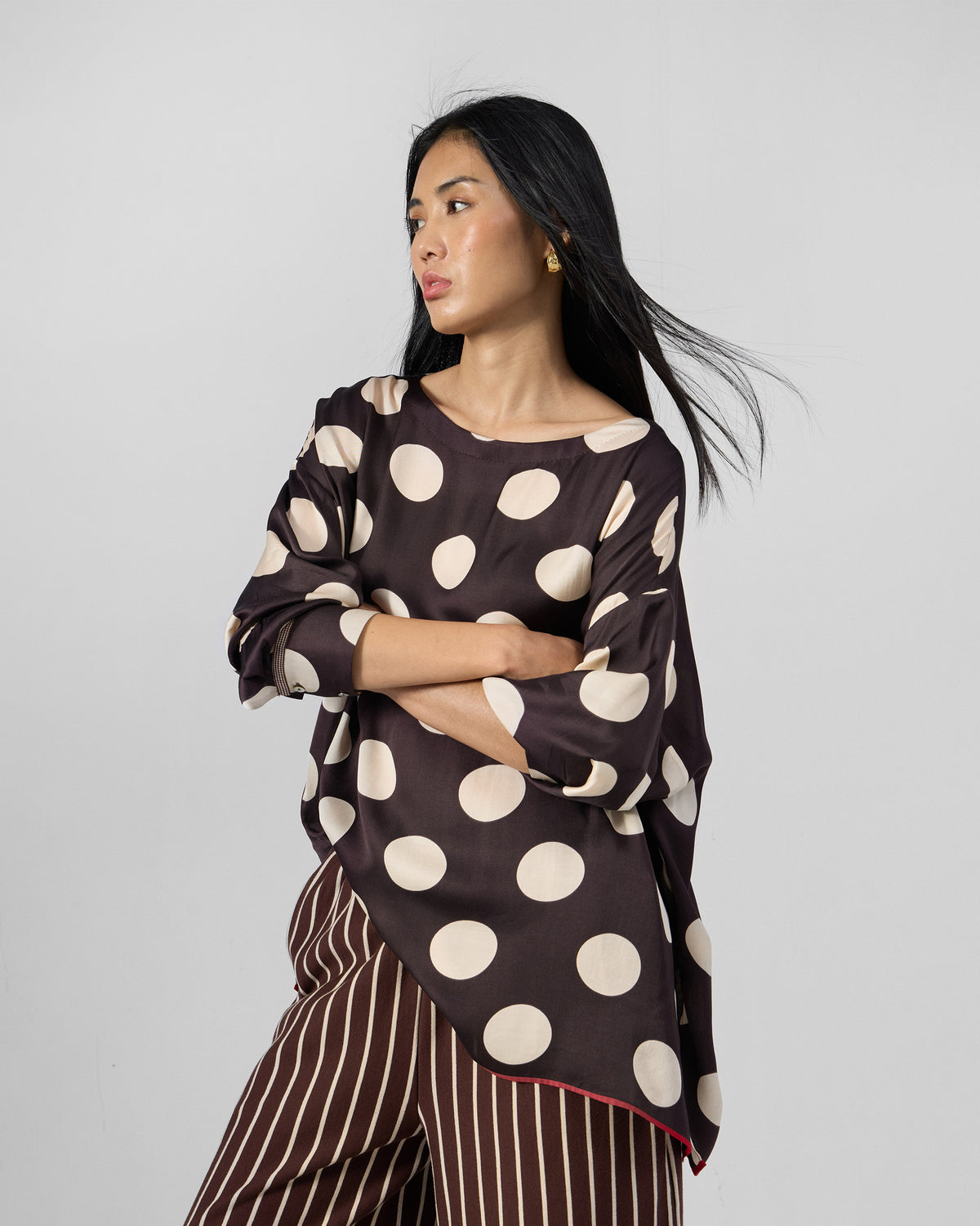 Person wearing a brown boat-neck top with large ivory polka dots.