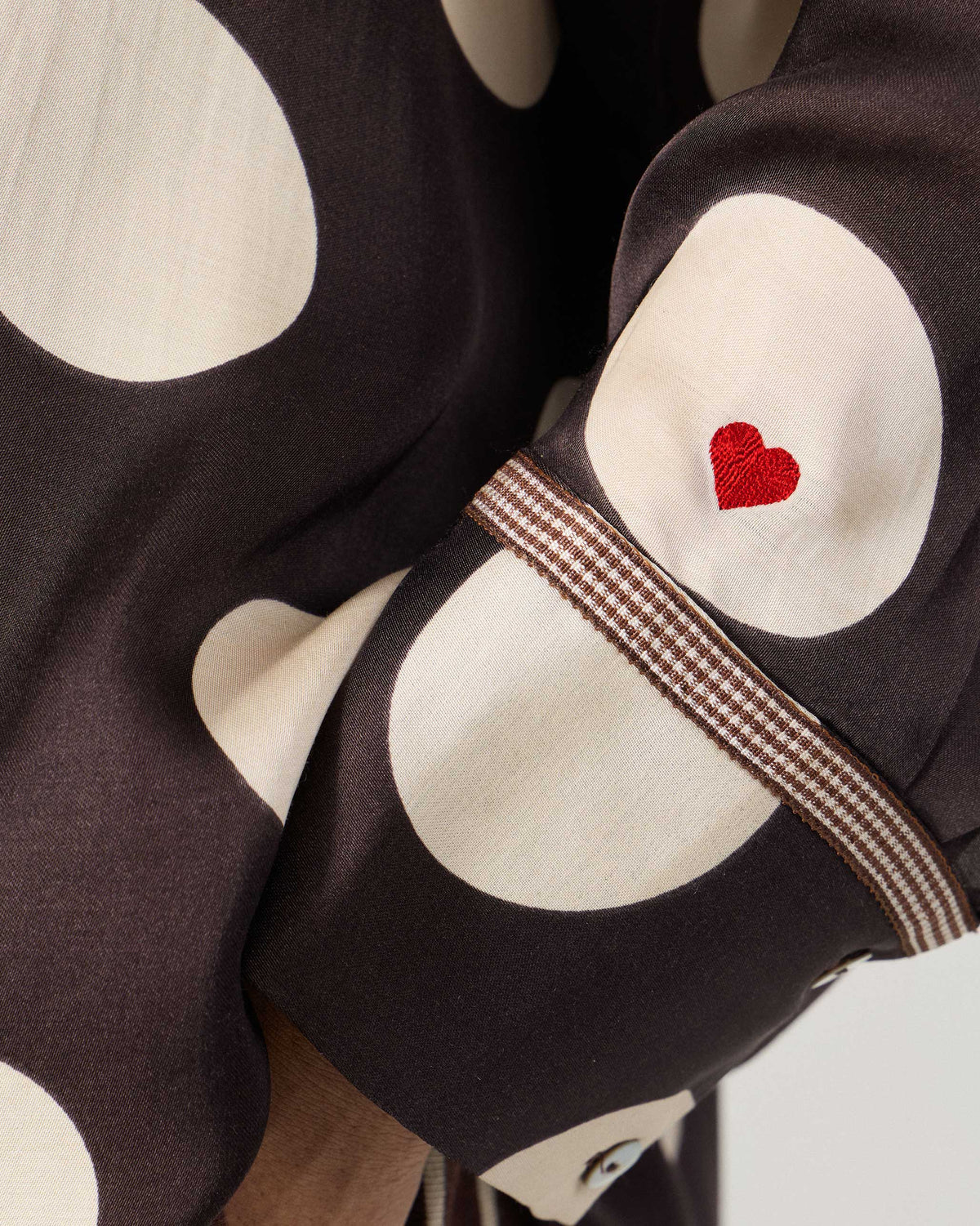 Close-up of a brown polka-dot sleeve with a red embroidered heart.