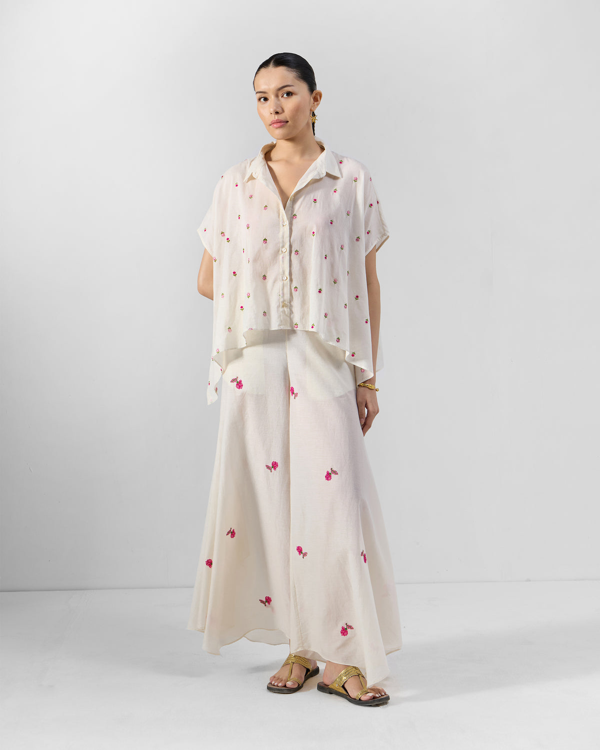 Person wearing an ivory embroidered shirt set with pink rosebuds.