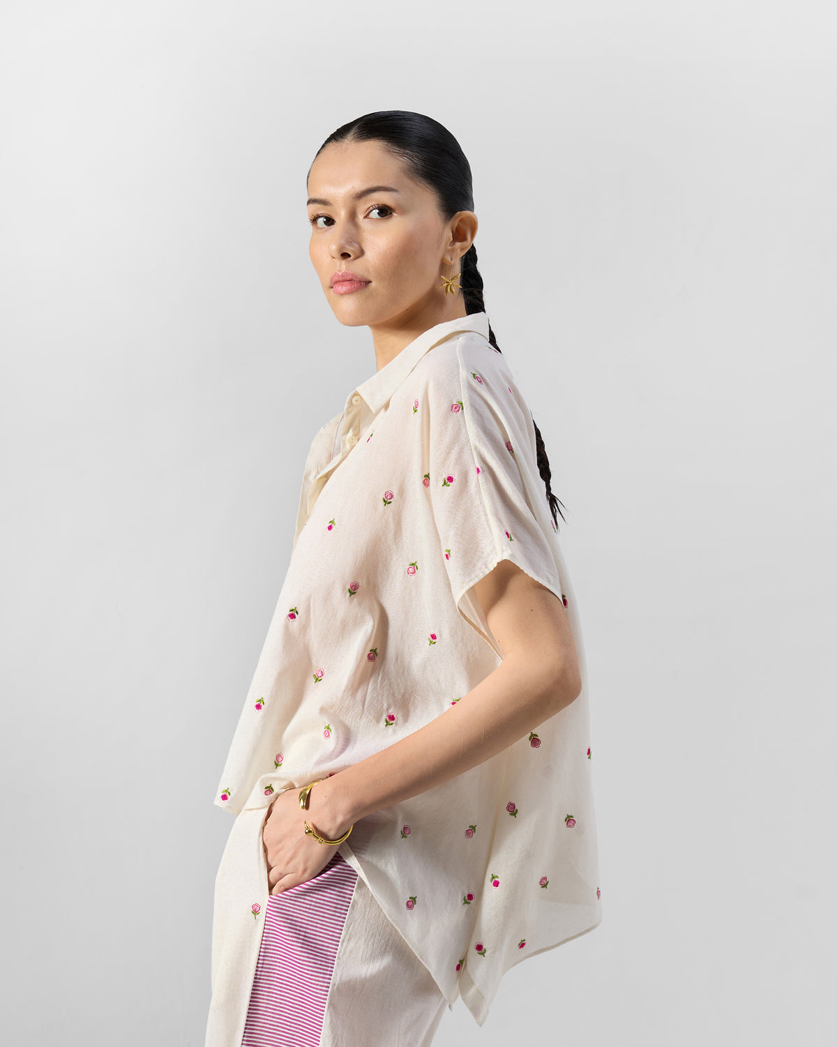 Side view of an ivory embroidered shirt set with pink striped pant panels.