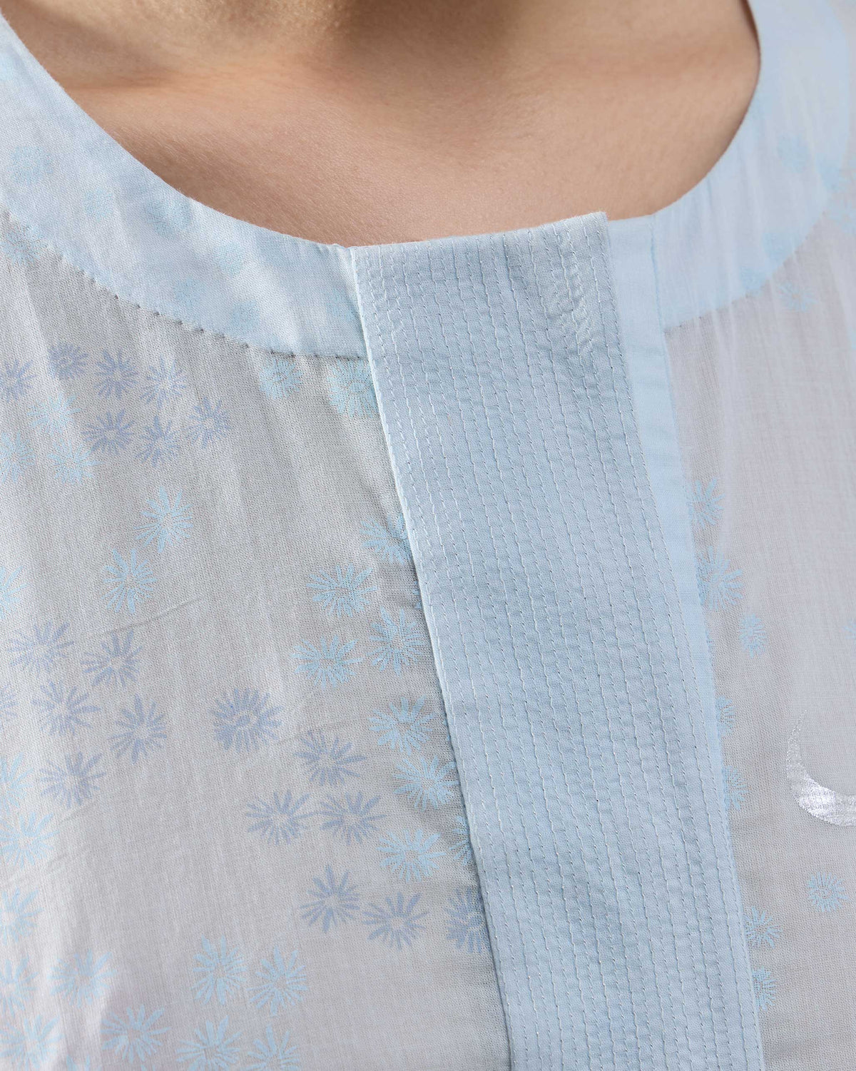 Close-up of a silver crescent moon on a pale blue Kolva Kurta.