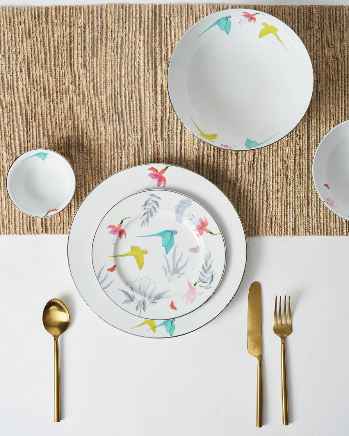 Plate and bowls of the Botanical Dinner set with bird motifs, seen from above.