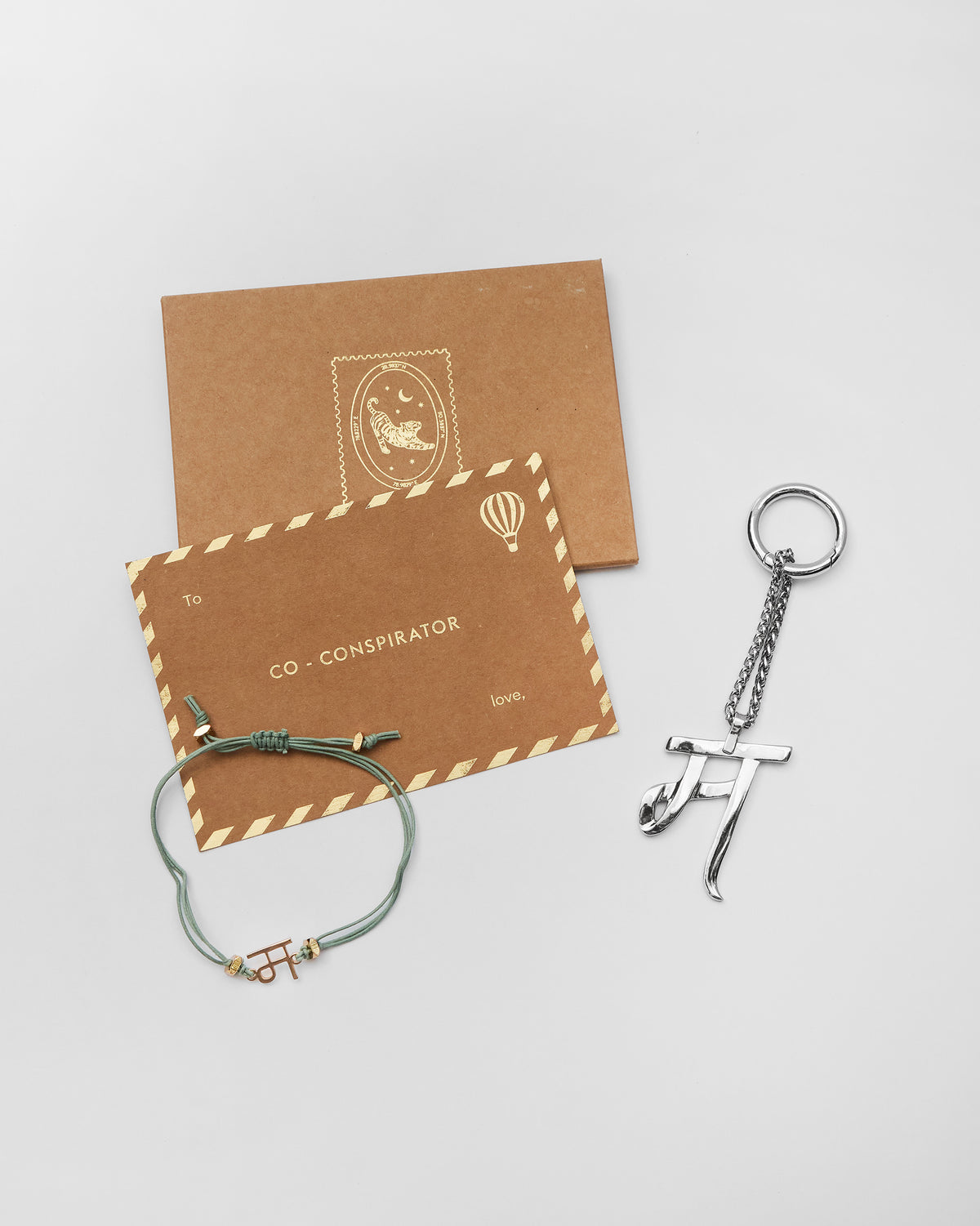 Alphabet M rakhi and bag charm with Nicobar gift cards.