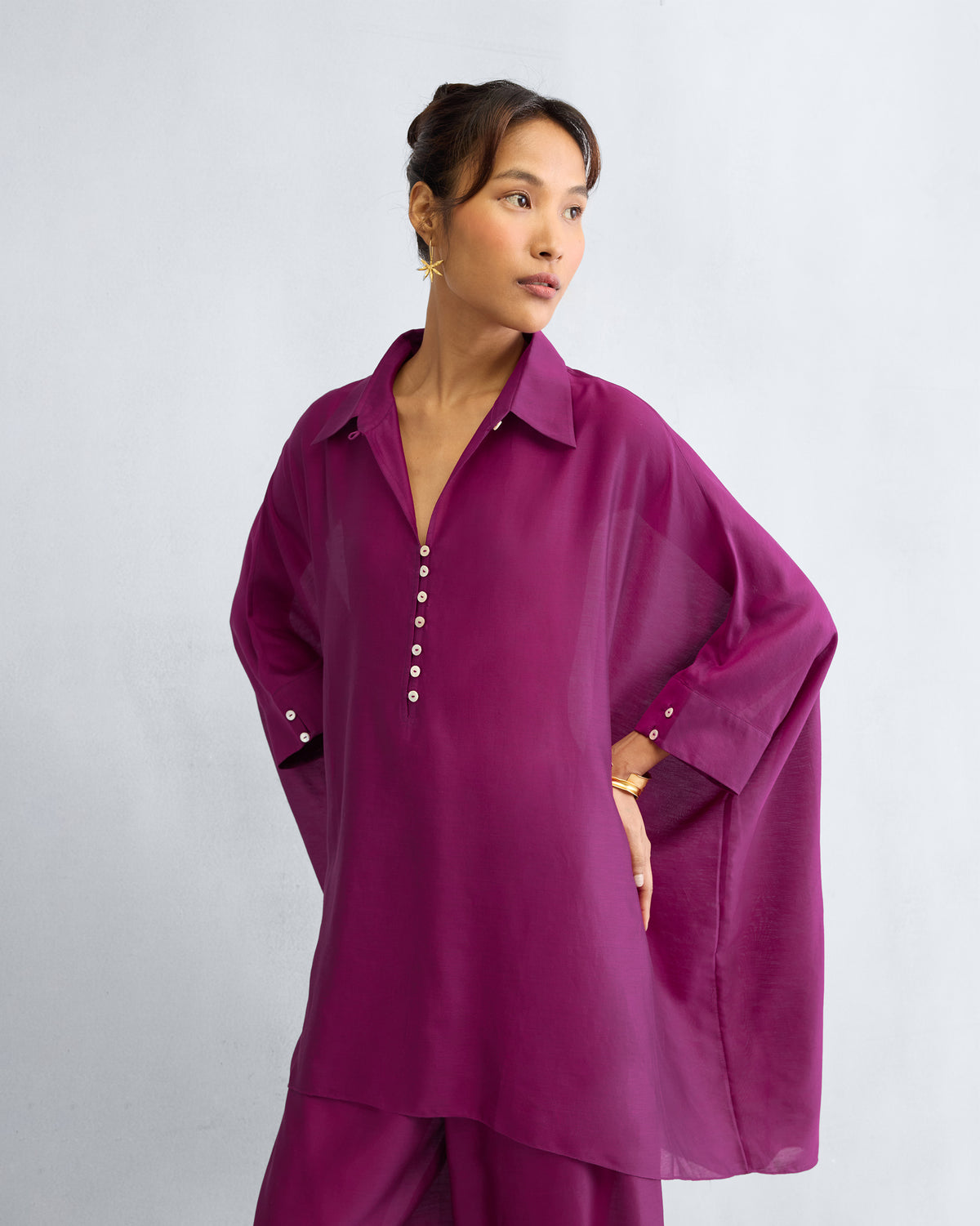 Person wearing a mulberry Hala tunic with wide sleeves.