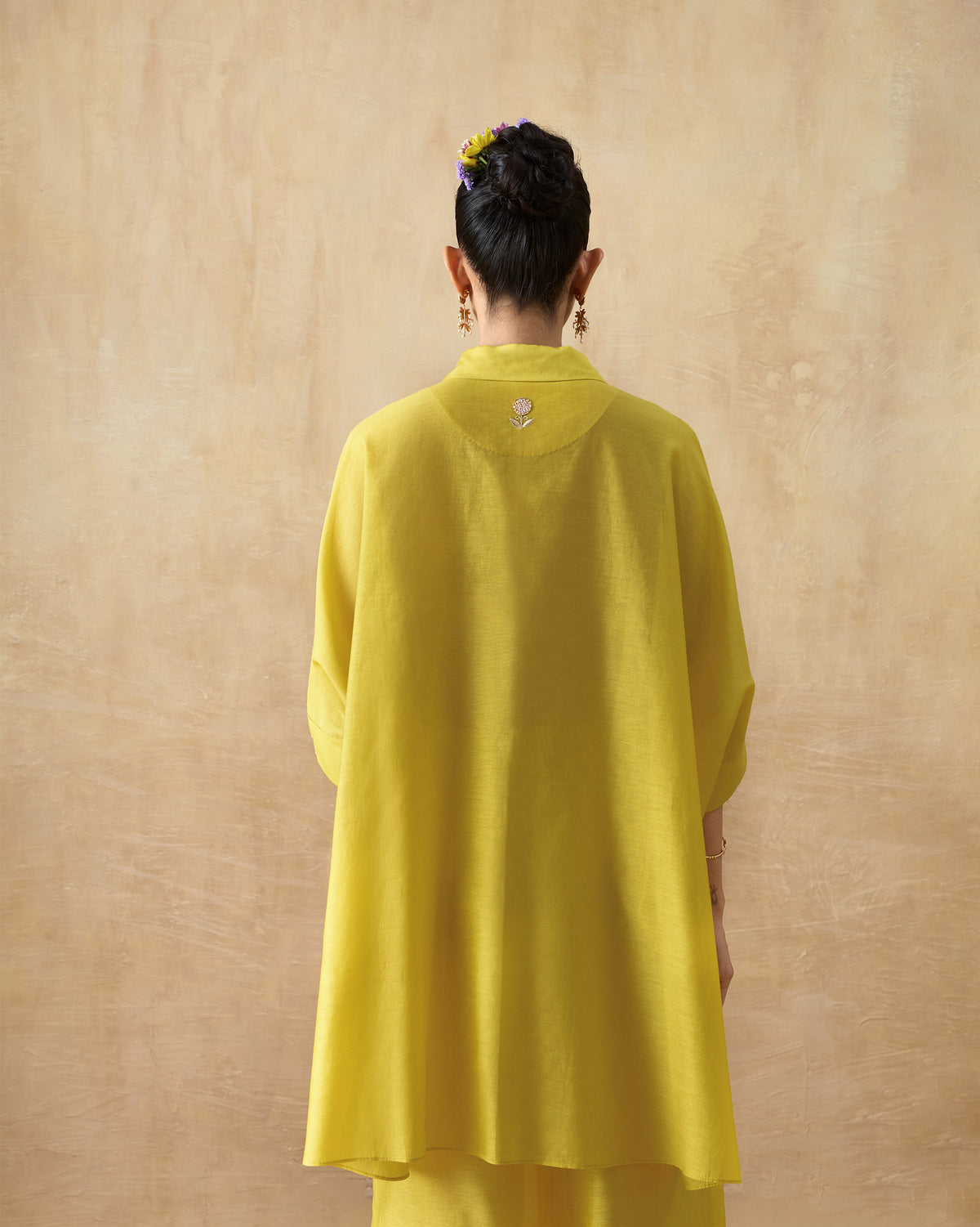 Back of a chartreuse tunic with a small flower motif on the yoke.