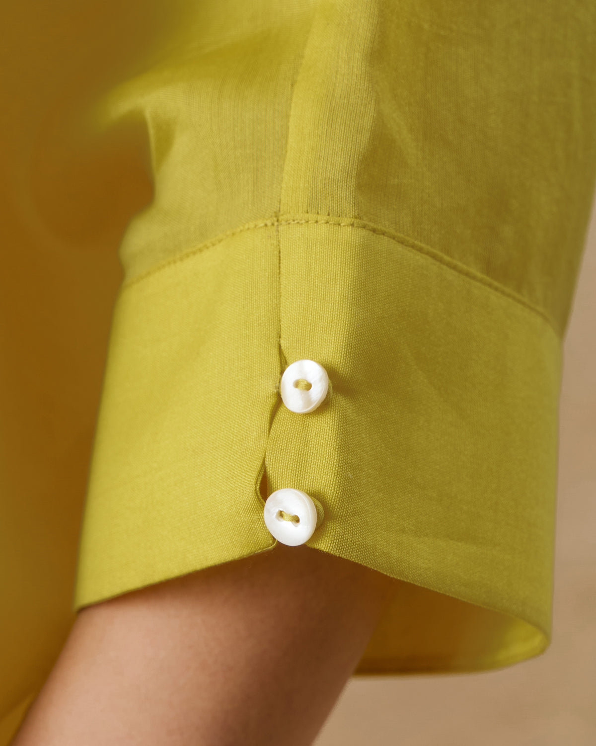 Close-up of a chartreuse tunic cuff with two small white buttons.