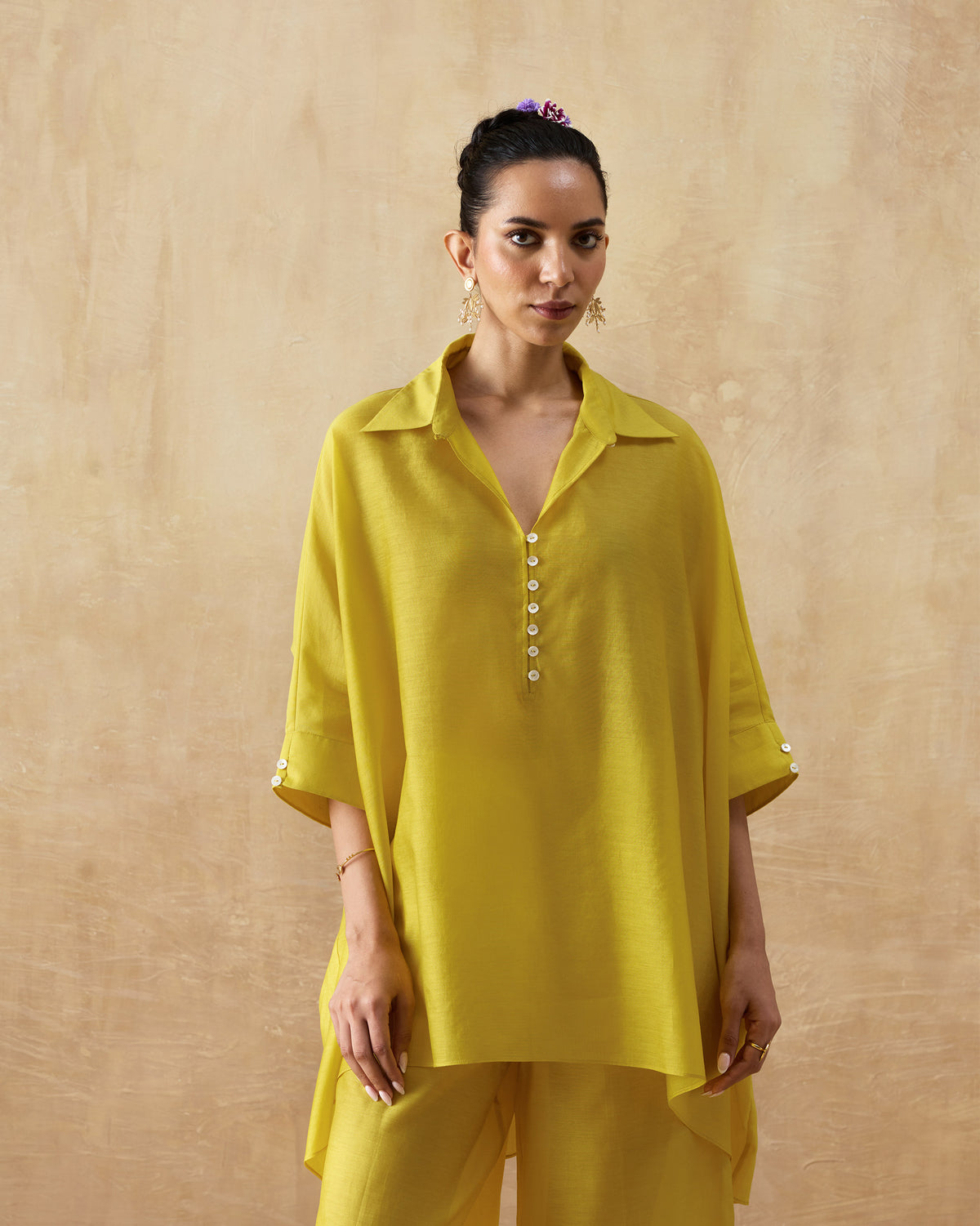 Person wearing a chartreuse tunic set with wide sleeves and a high-low hem.