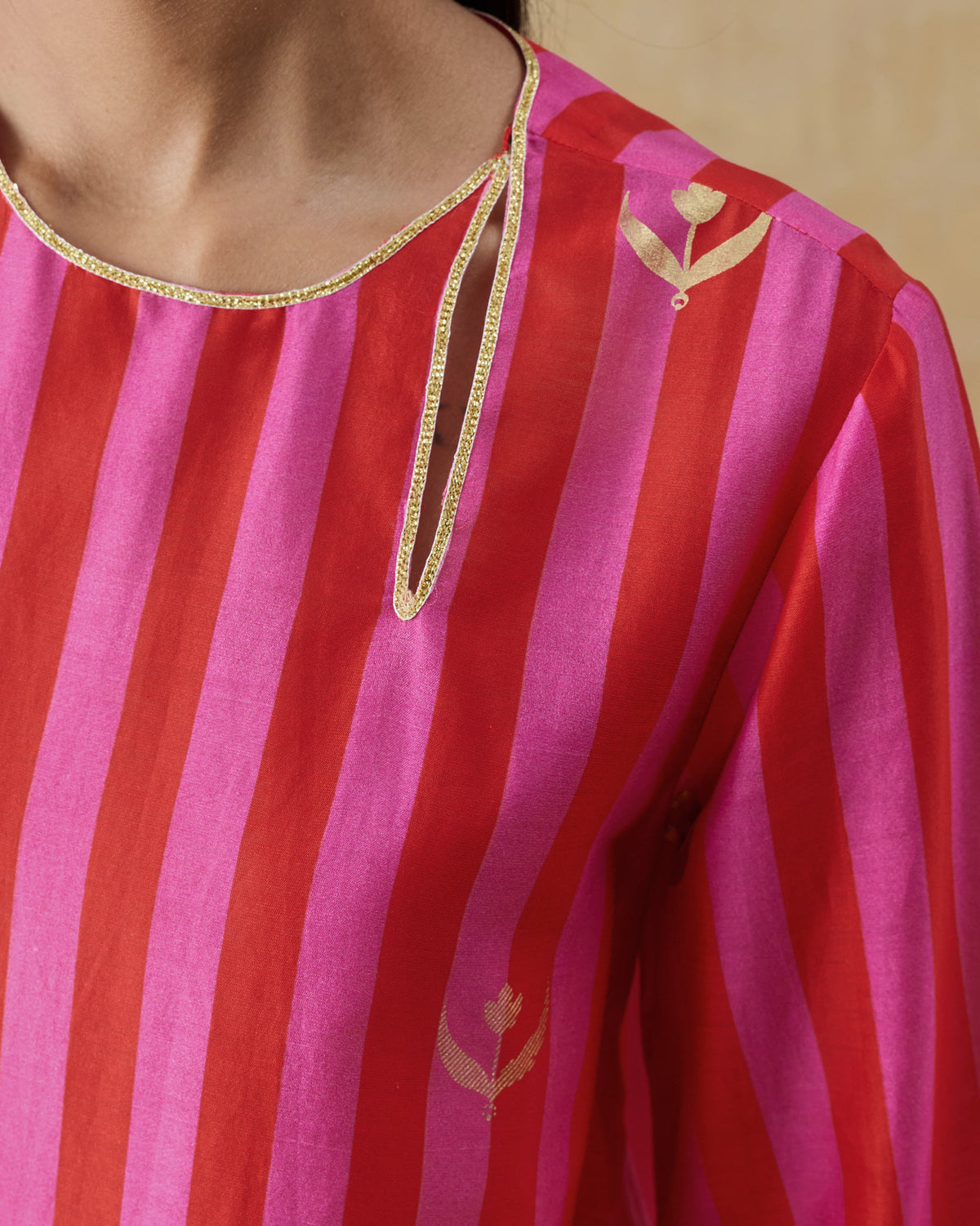Close-up of a red and berry striped kurta neckline with a gold keyhole.