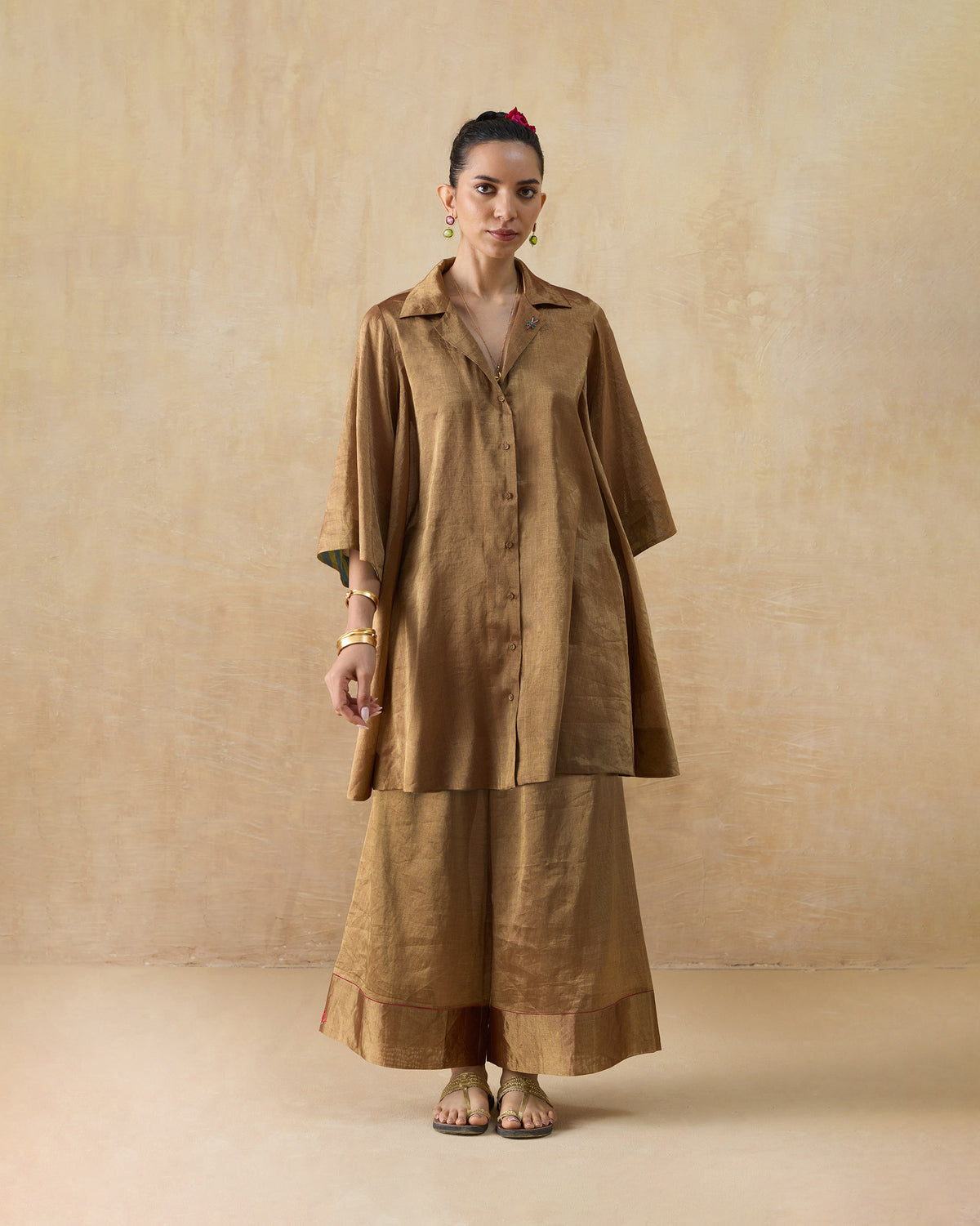 Person wearing a metallic gold shirt set with wide-leg pants.