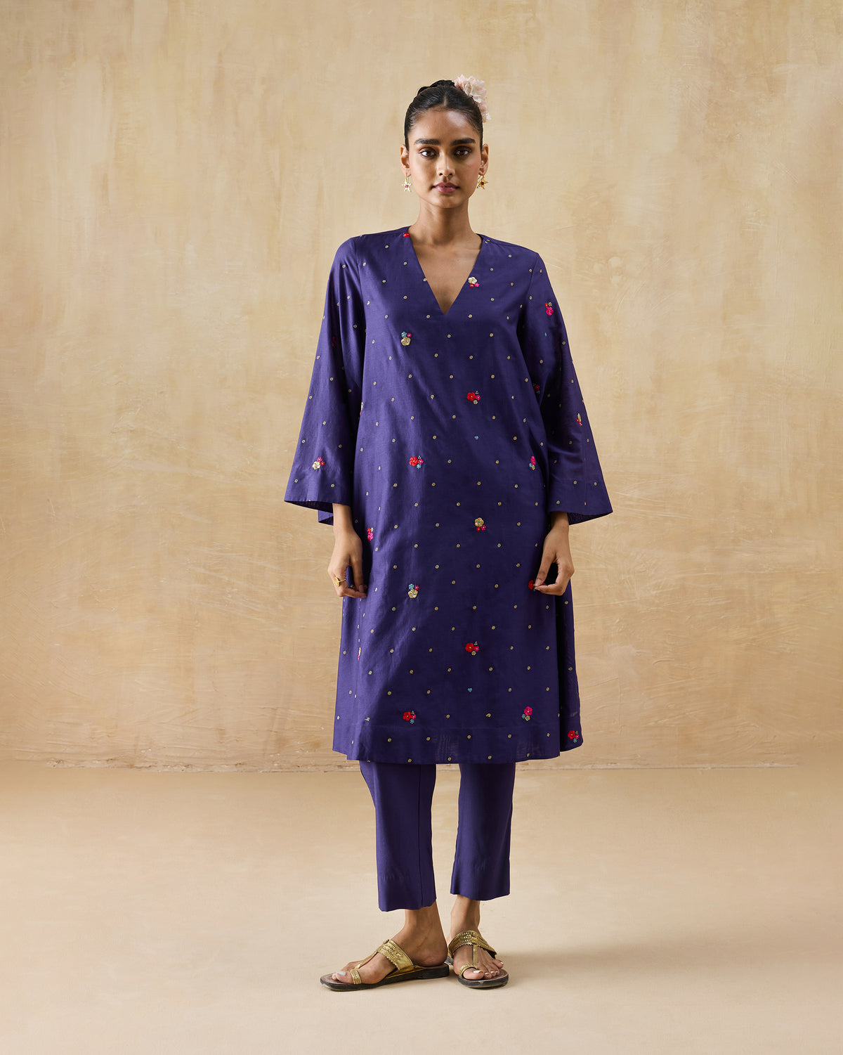 Person wearing a purple Nebula Kurta Set with gold butis and pink florals.