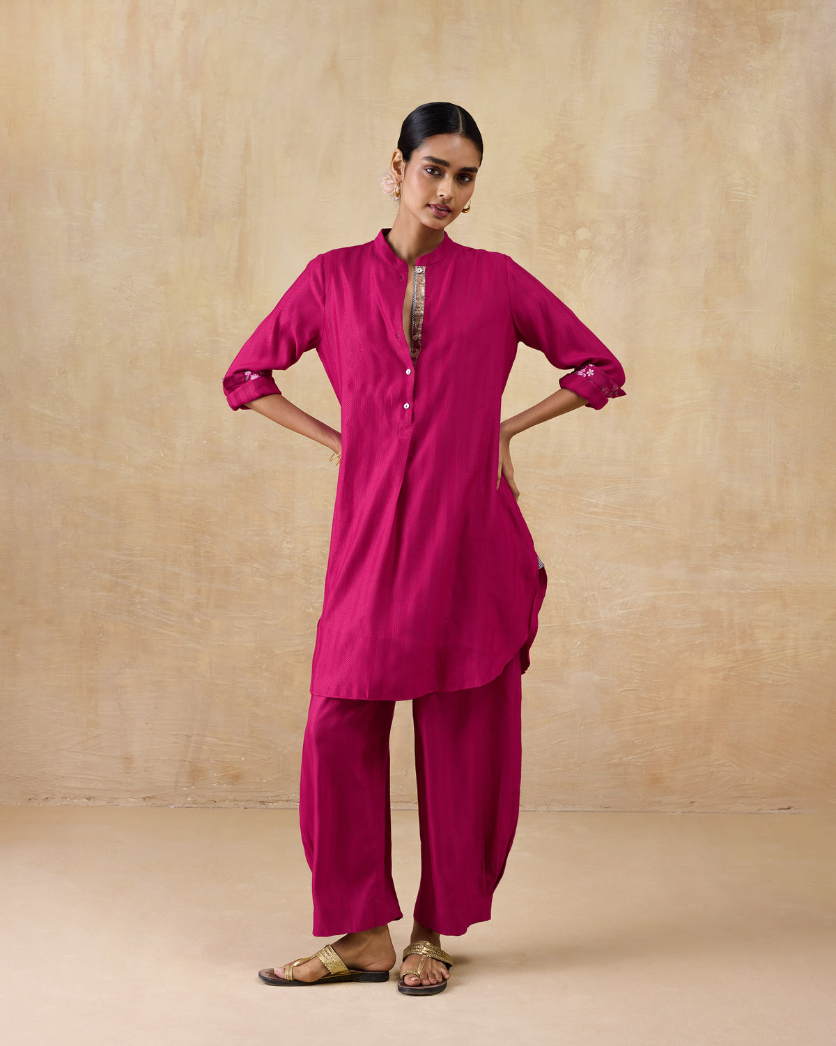 Person wearing a berry pink long kurta set with rolled sleeves and wide pants.
