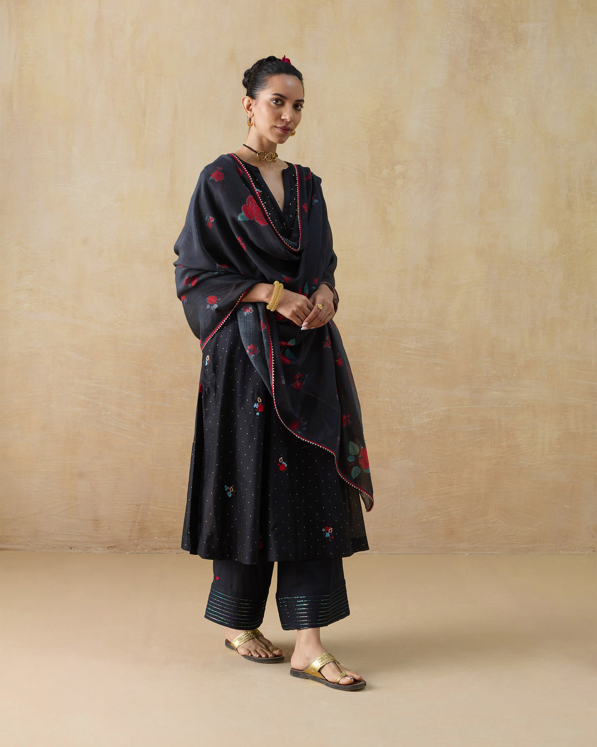 Person wearing a black Moonbeam kurta set with a red rose-print dupatta.