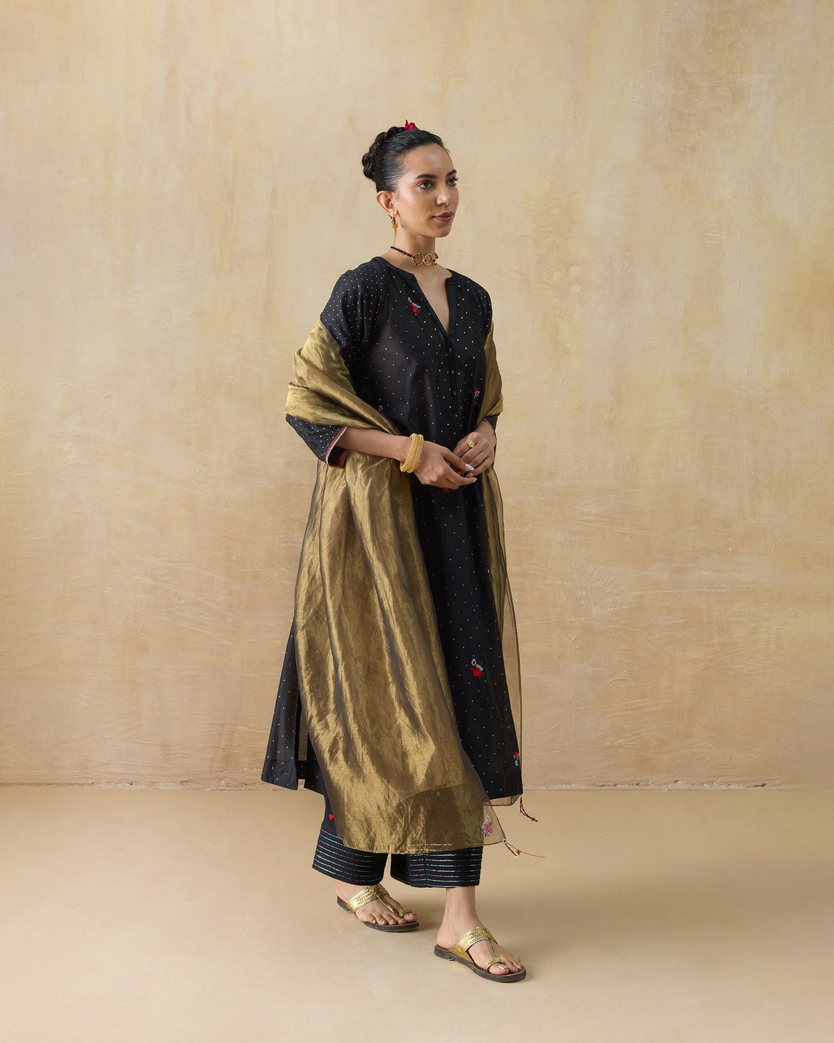 Side view of a black Moonbeam kurta set wrapped in a gold sheer dupatta.
