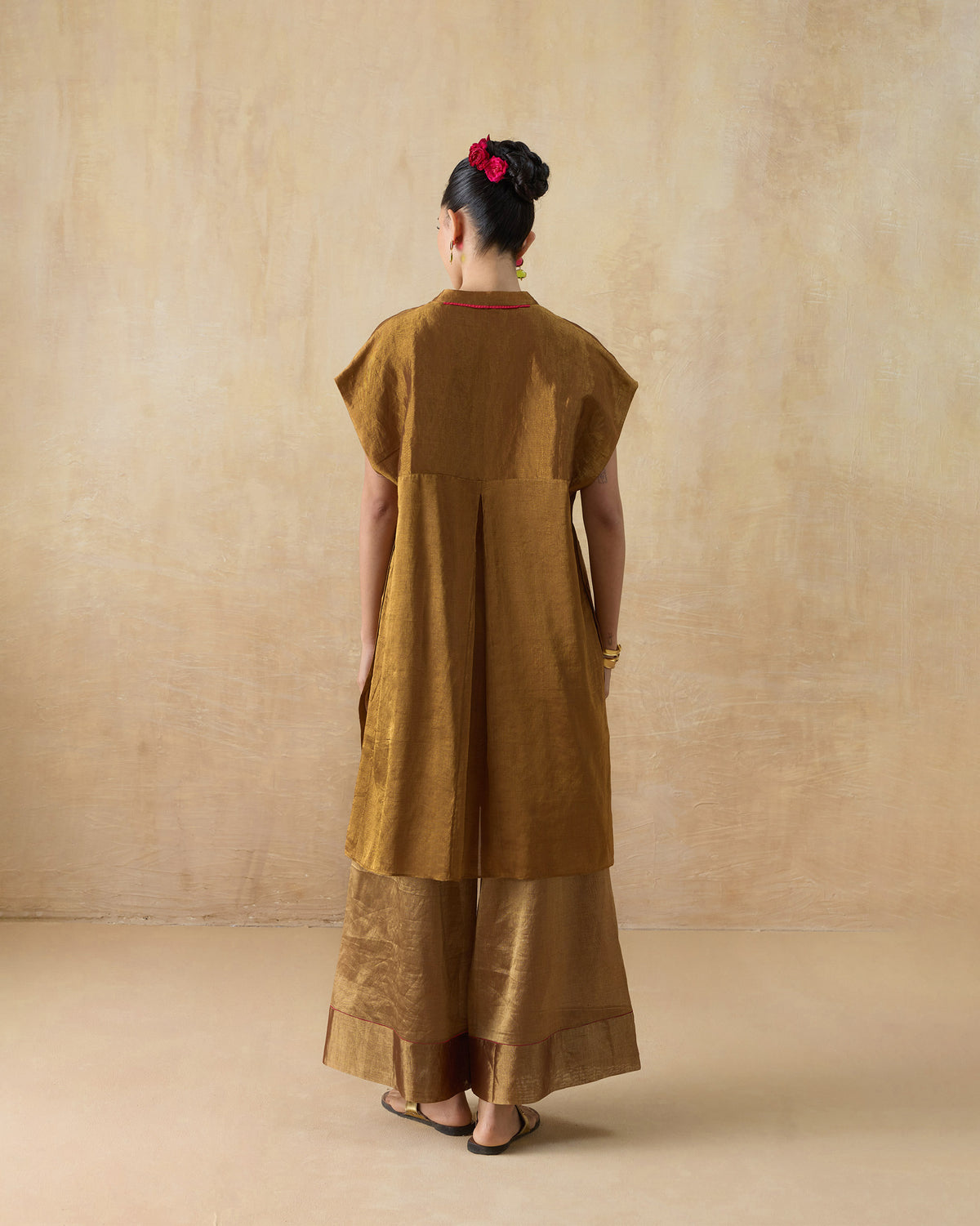 Back of the Tango kaftan worn by a person, in bronze gold with a pleat down the back.