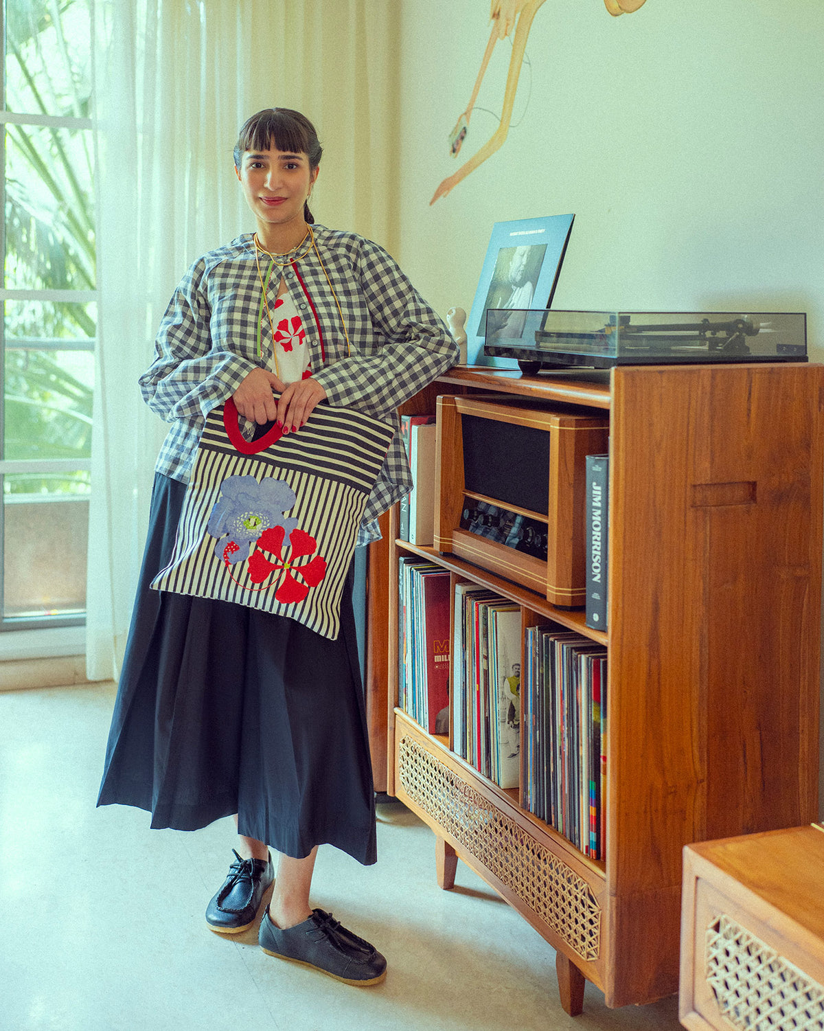 Person wearing a white and red floral Kiva top under an open gingham shirt.