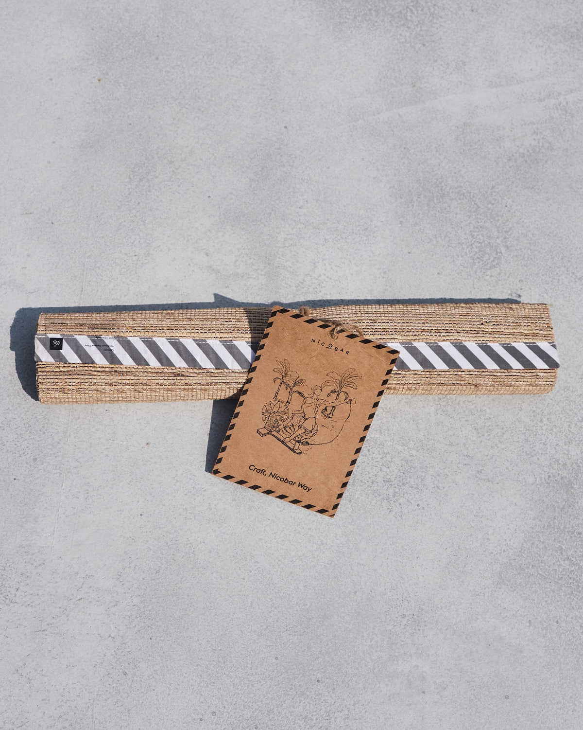 Rolled banana fibre runner wrapped with a striped band and Nicobar craft tag.