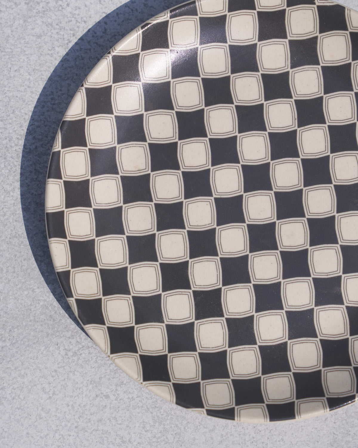 Close-up of the Fez quarter plate showing its charcoal checker tile motif.