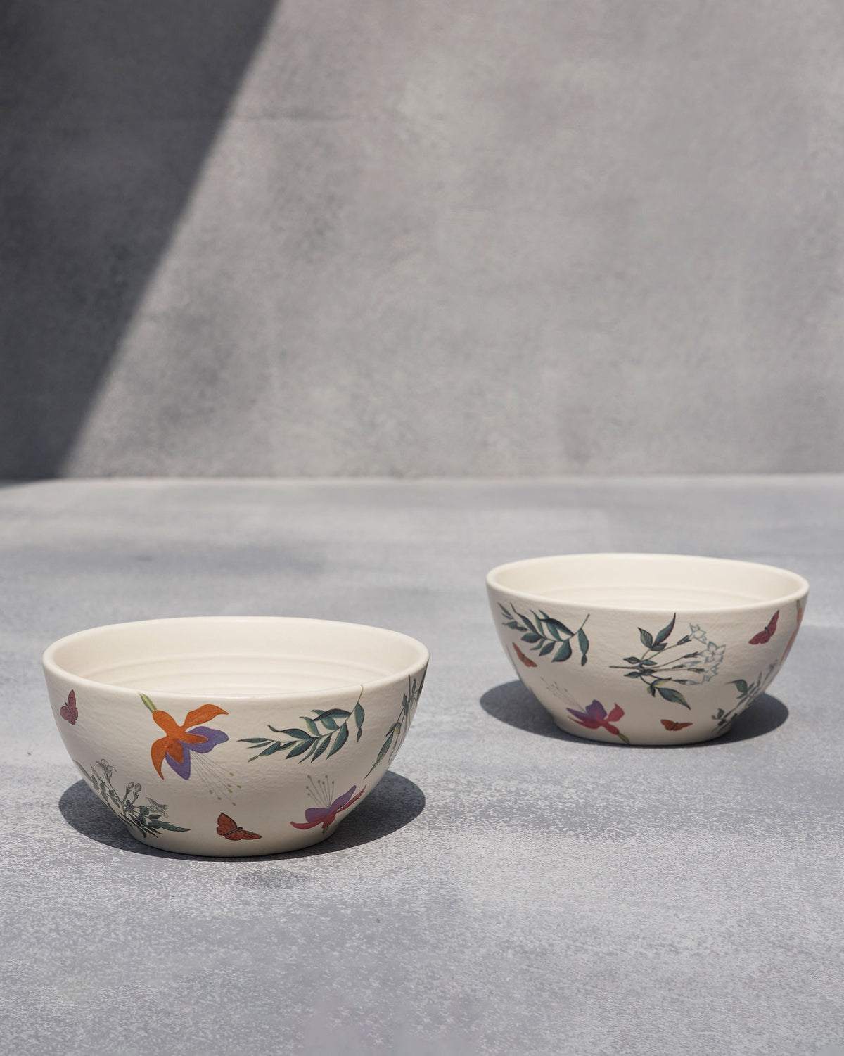 Pair of Botanical Cereal Bowls on a grey surface with floral print.