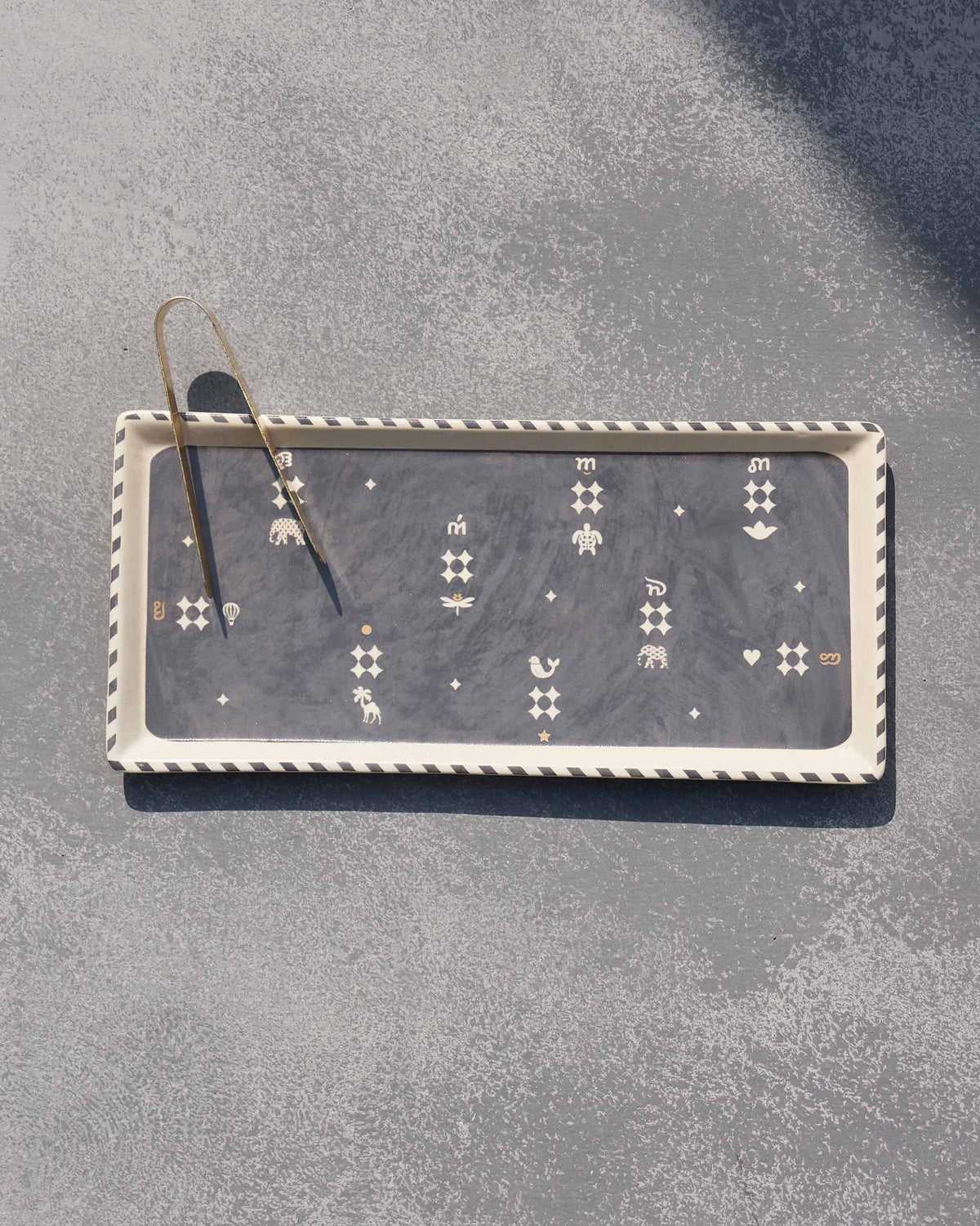 Nizara cookie tray with brass tongs and white animal and star motifs.