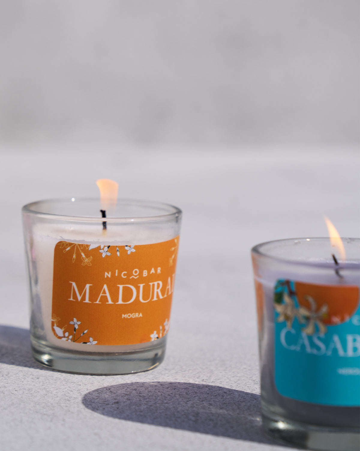Close-up of a lit Madurai mogra Trio Candle votive with an orange label.