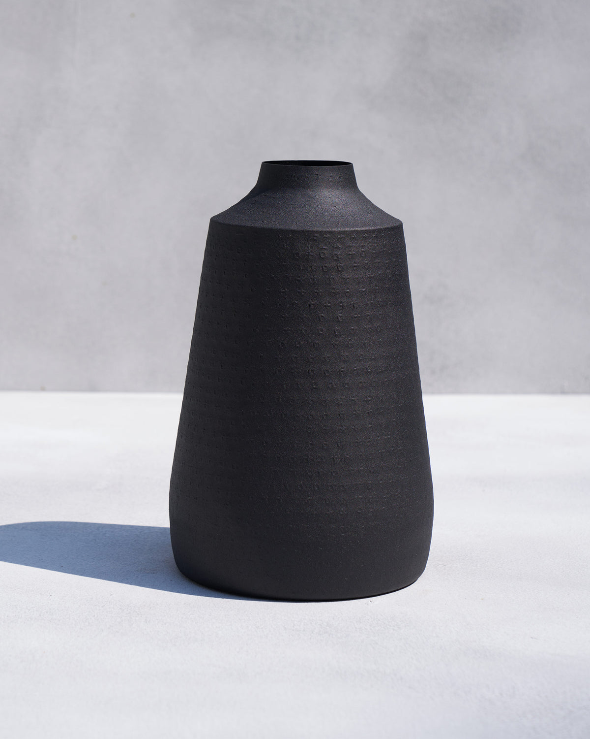 Nadi vase in matte black with a dotted texture on the body.