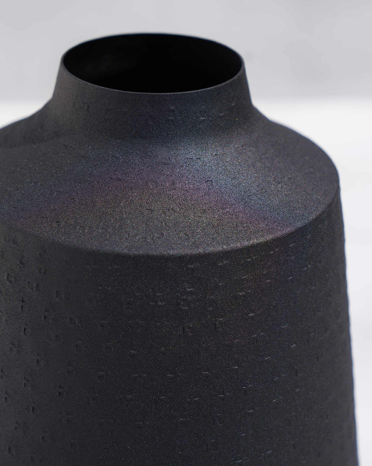 Close-up of the Nadi vase neck showing its dotted matte black texture.