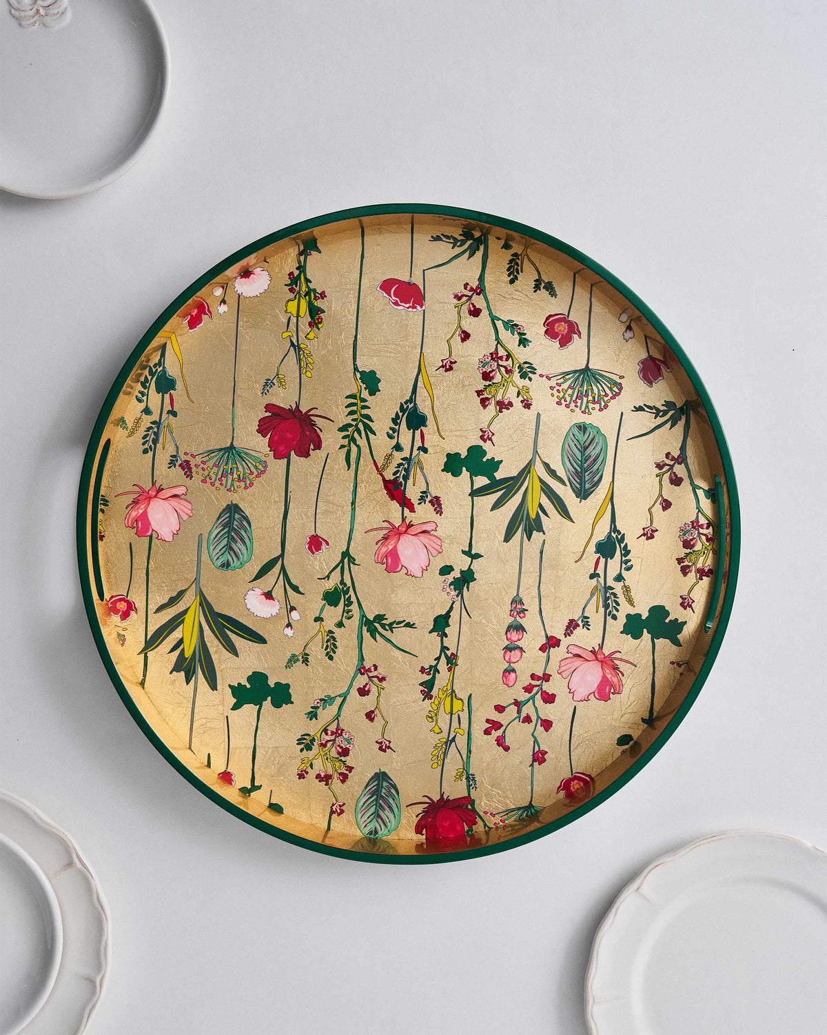 Overhead view of the Mahi Round Tray with hanging flower sprigs on its gold base.