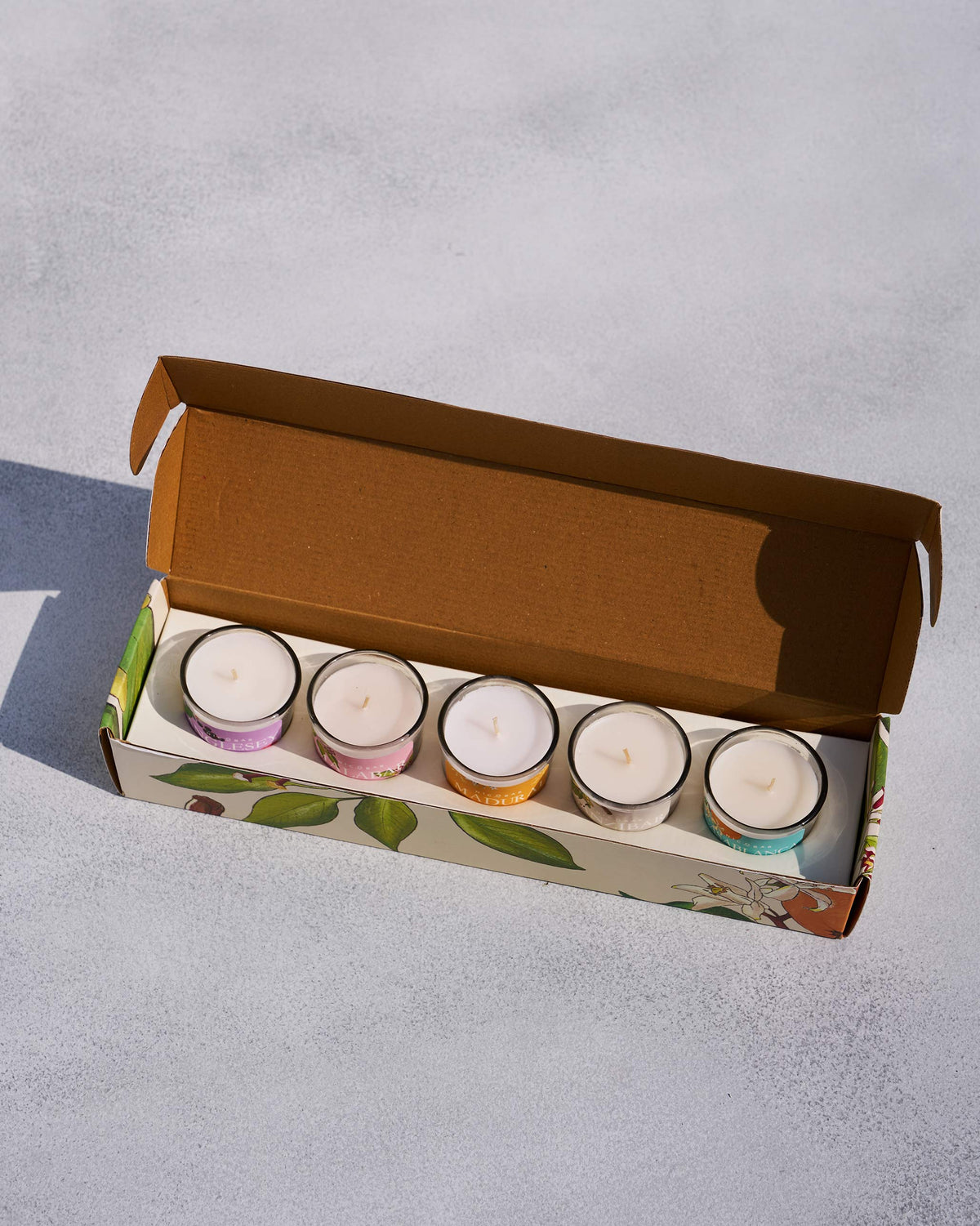 Open Nicobar gift box holding five jar candles in a tray.
