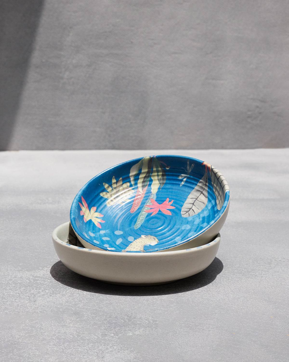 Stacked Mahi shallow bowls with a blue leopard and foliage interior.
