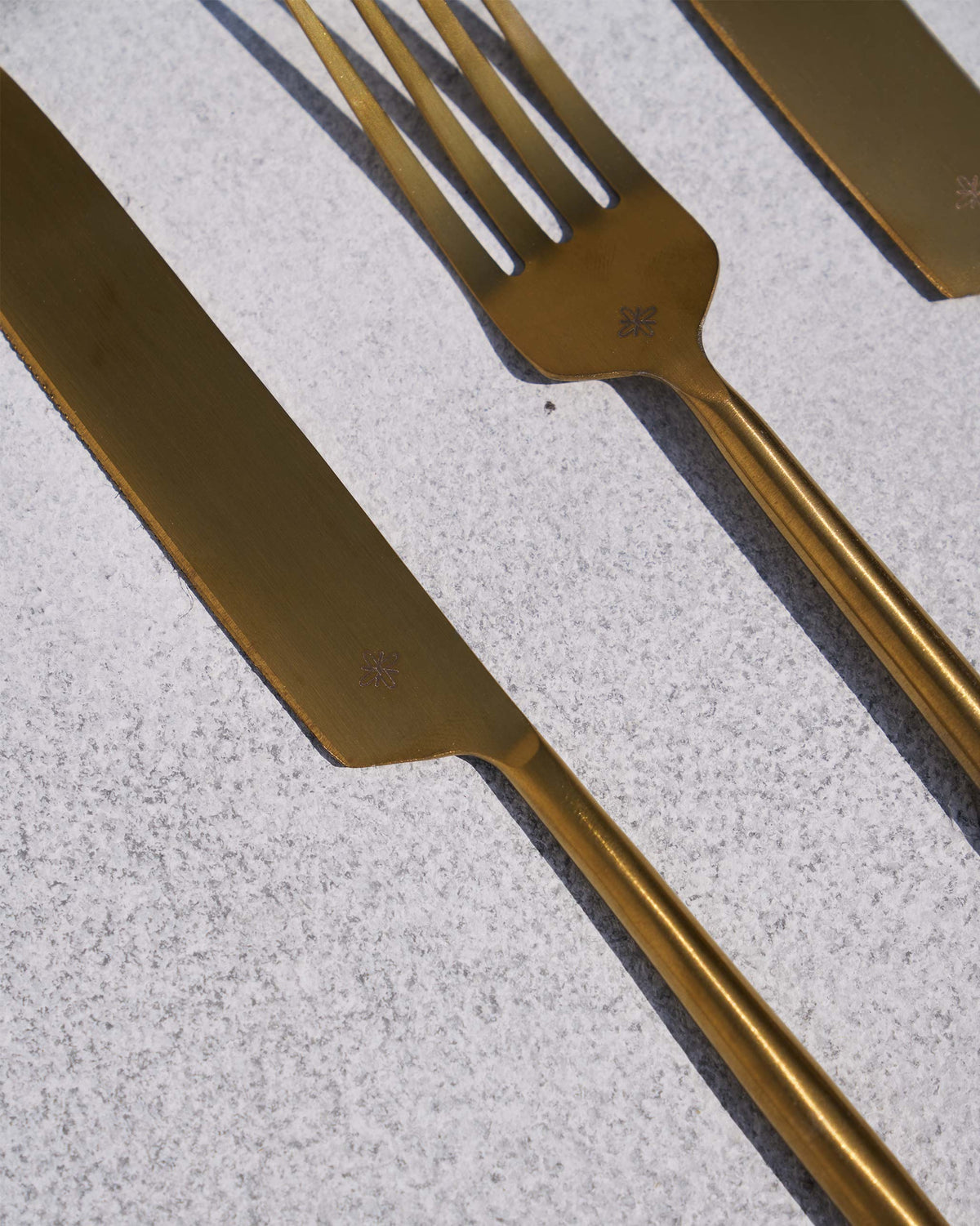 Close-up of gold Sitara cutlery showing a small star mark.