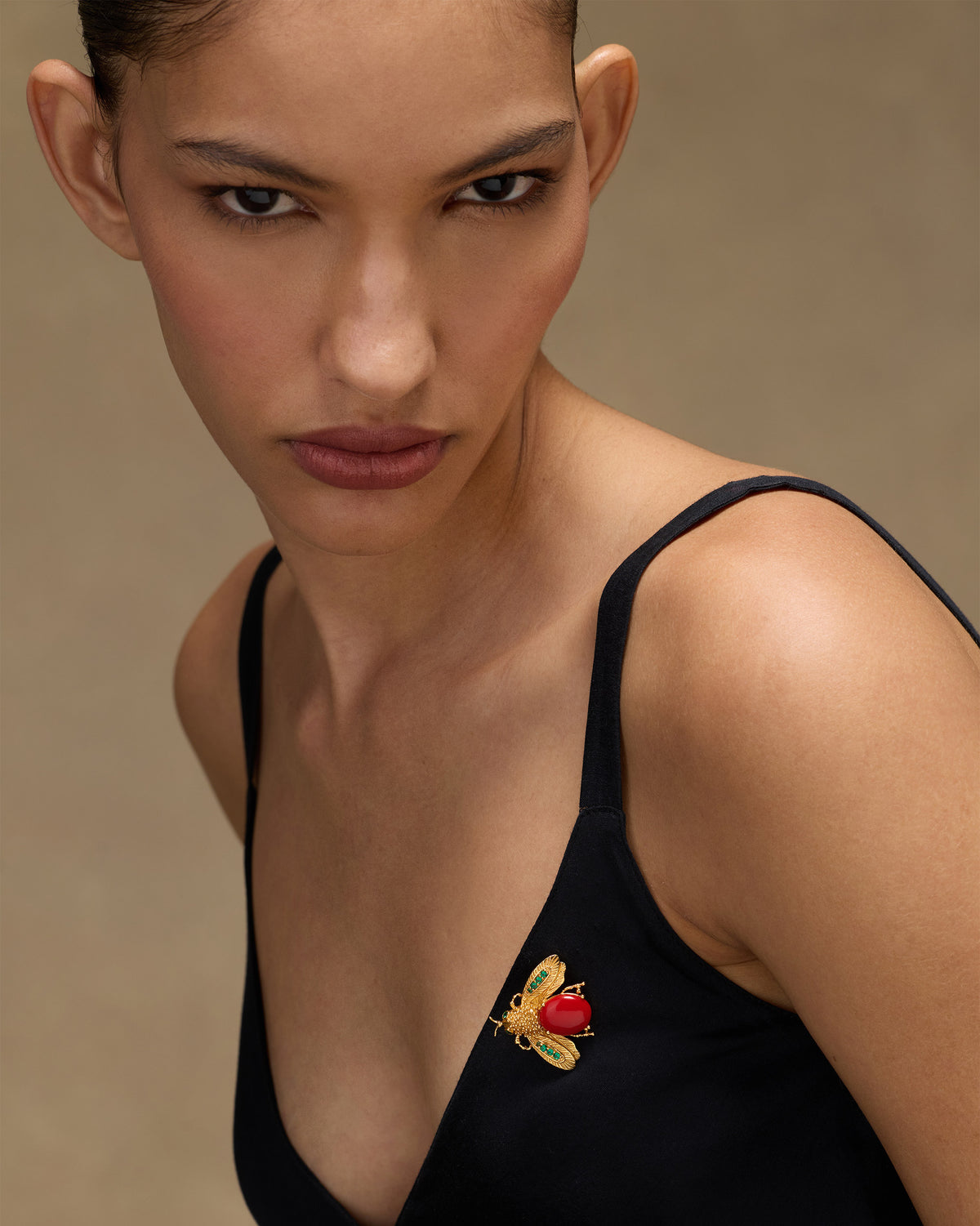 Person wearing a gold Bug brooch with a red stone insect motif.