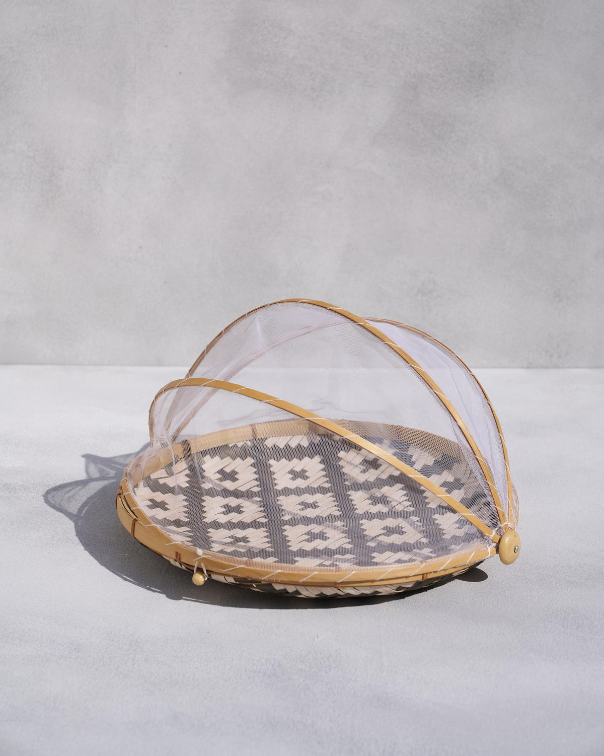 Side view of Alpine food cover with a mesh dome over a woven base.