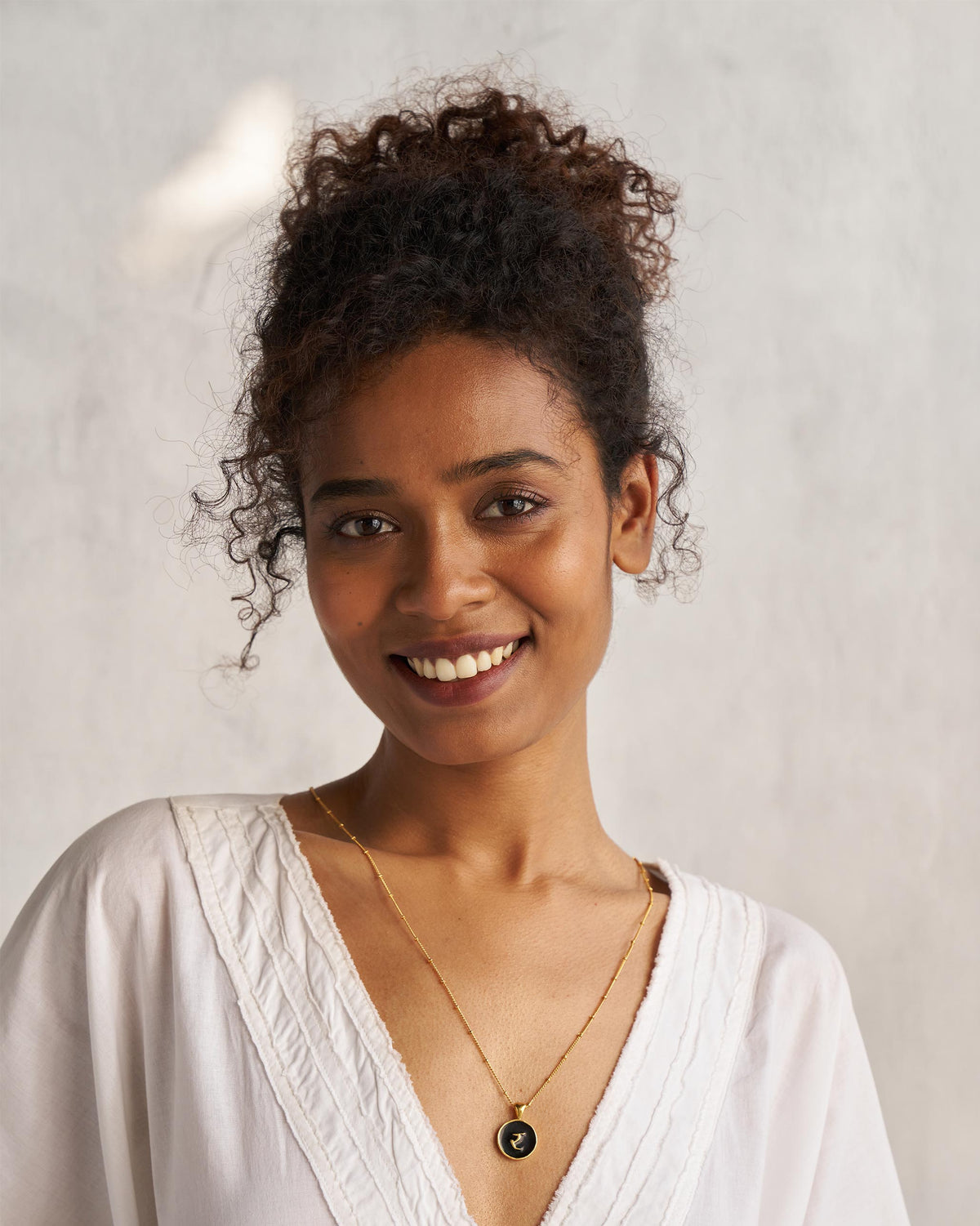 Person wearing a black and gold Alphabet R charm necklace.