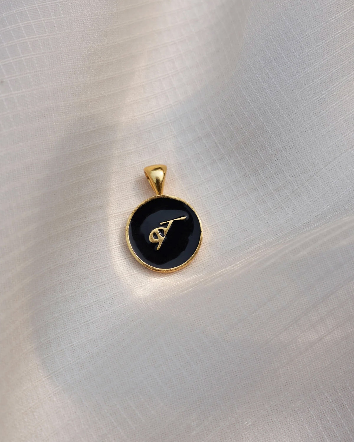 Close-up of a black and gold Alphabet B charm with a gold letter.