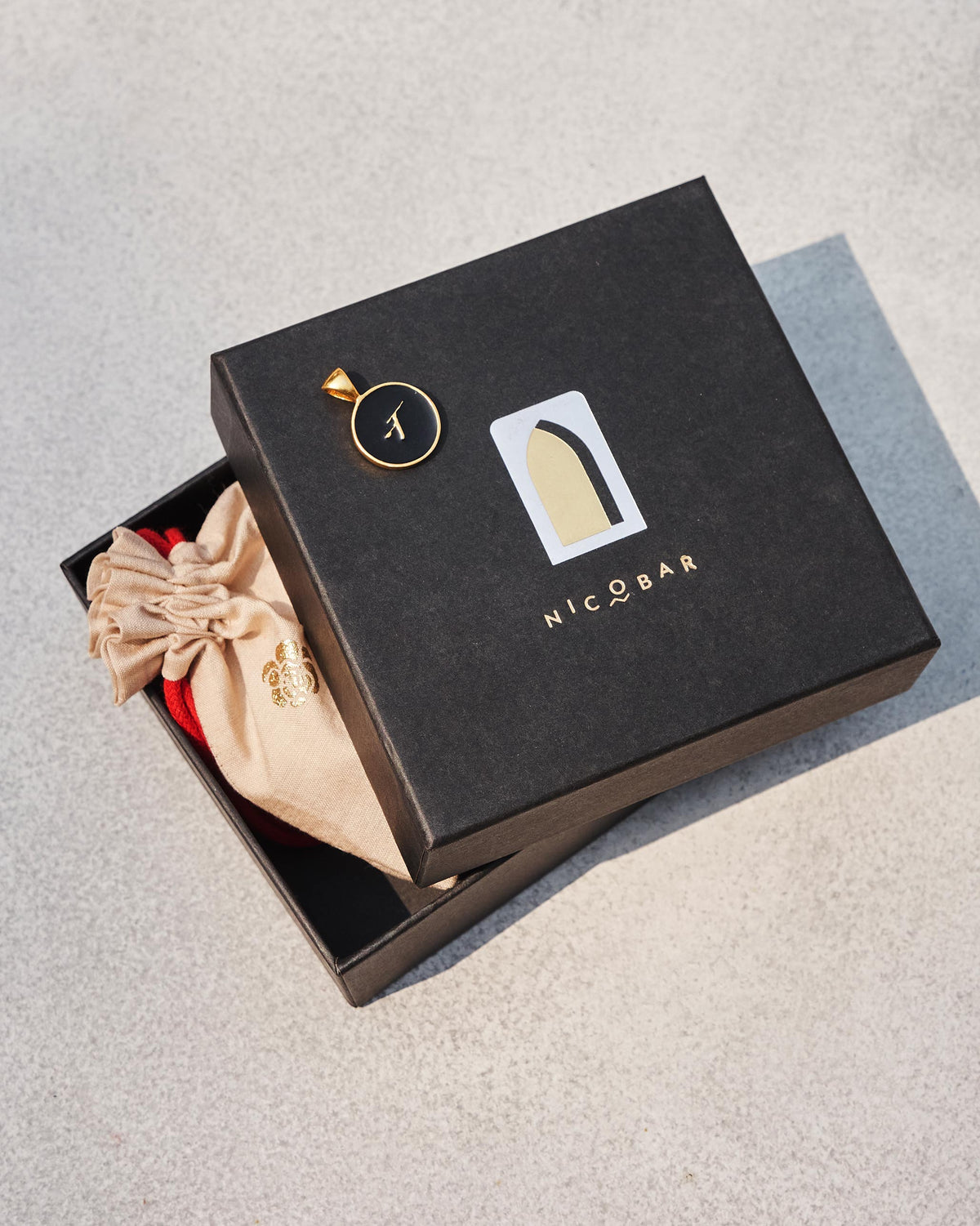 Black and gold Alphabet N charm on a Nicobar gift box.