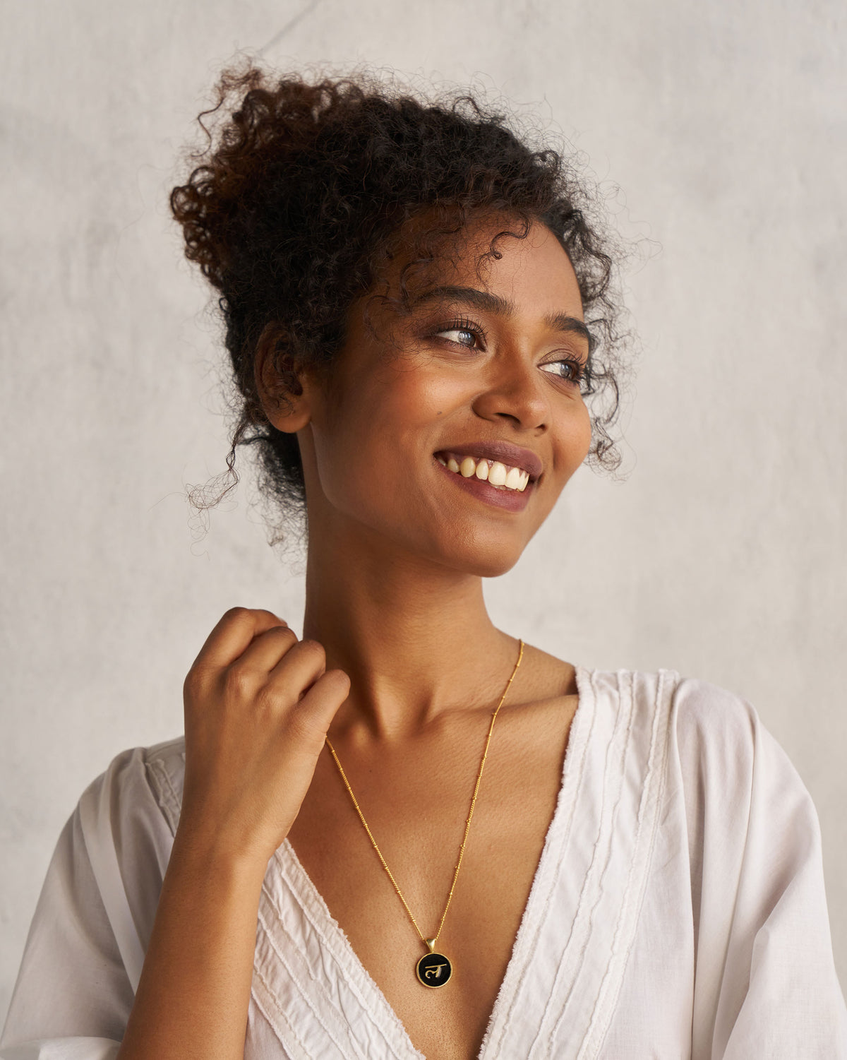Person wearing a black and gold Alphabet L charm necklace.