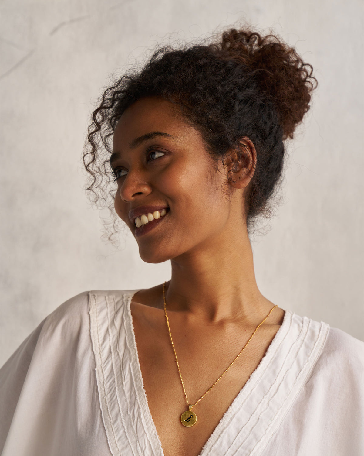 Person wearing a gold Alphabet L charm on a fine chain.