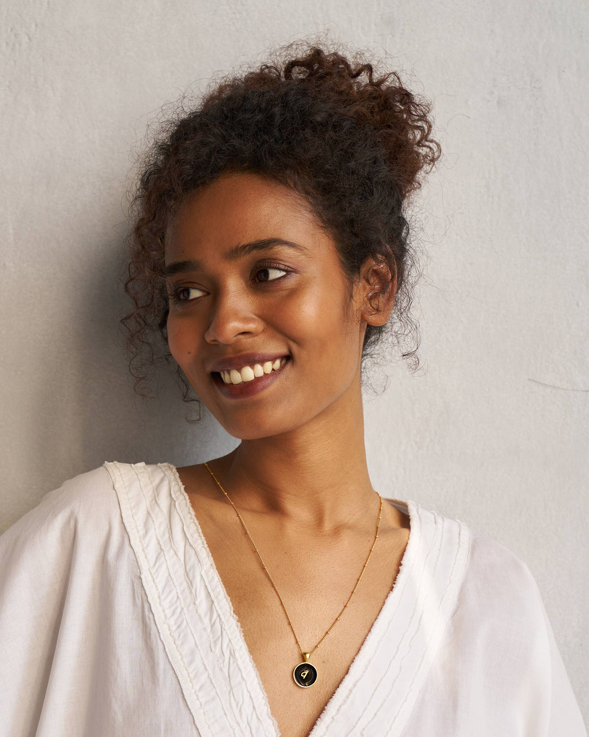 Person wearing a black and gold Alphabet V charm necklace.